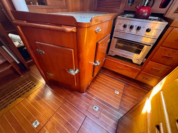 Wooden galley interior of 1983 Tayana 52 Aft Cockpit yacht with stove and cabinetry.