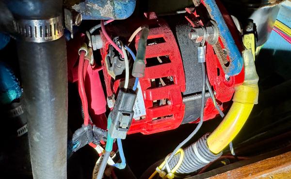 Engine compartment of 1983 Tayana 52 Aft Cockpit with visible wiring and alternator.