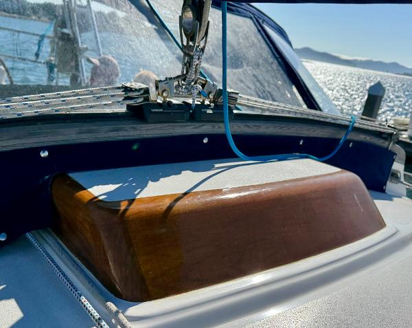1983 Tayana 52 Aft Cockpit sailboat detail with wooden hatch and ocean backdrop.