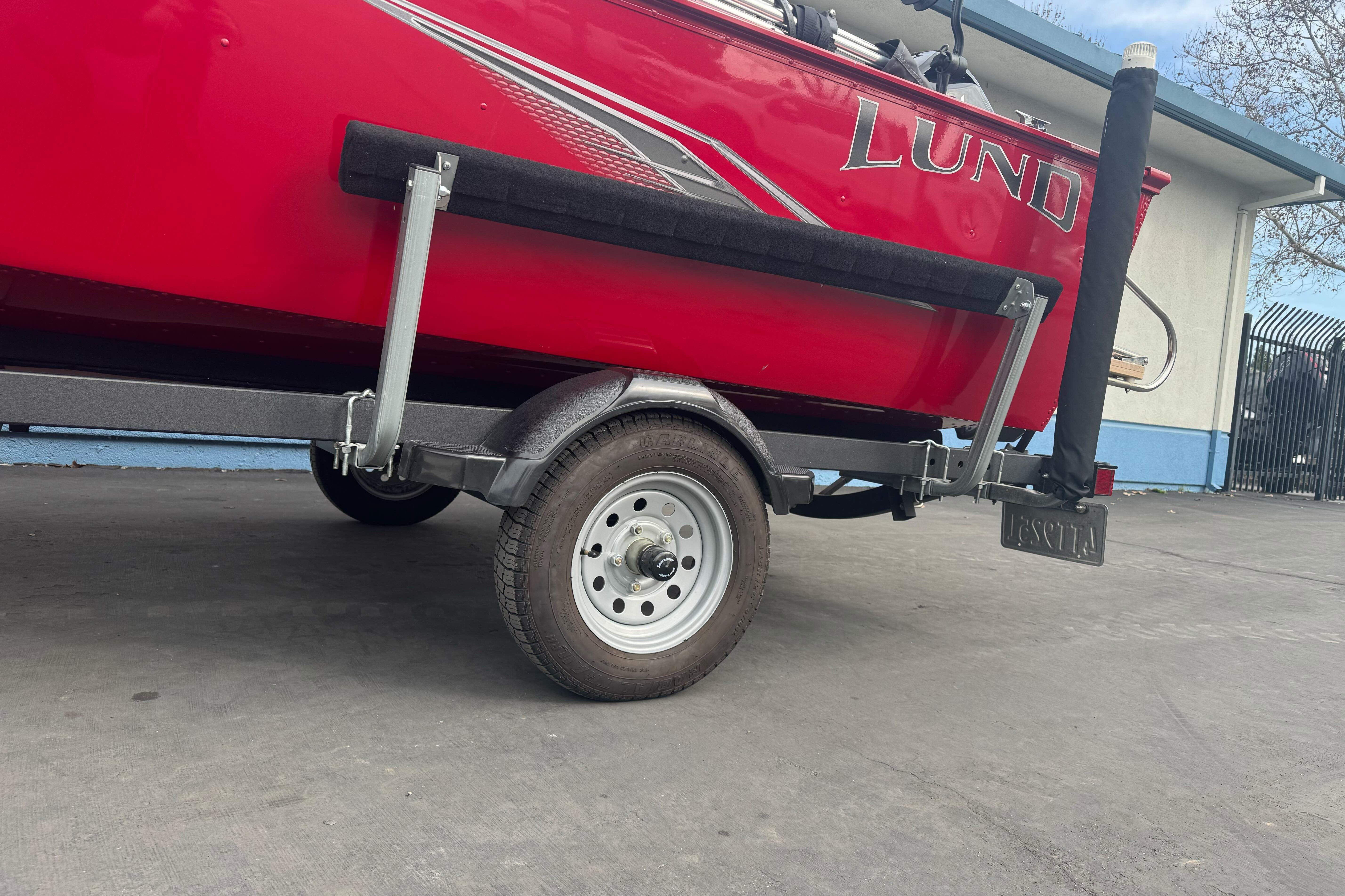 Red 2021 Lund 1650 Angler SS boat on trailer, parked outdoors.