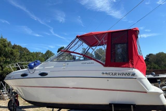 2000 Four Winns 238 Vista boat with red canopy, parked outdoors under blue sky.