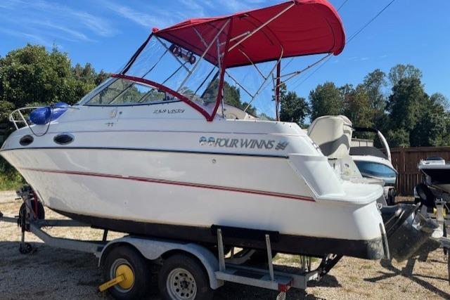 2000 Four Winns 238 Vista boat with red canopy on trailer, parked outdoors.