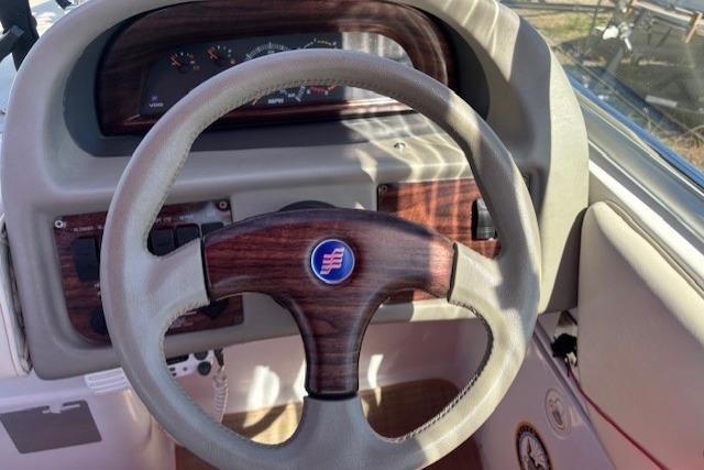 Steering wheel of a 2000 Four Winns 238 Vista boat with wood accents.