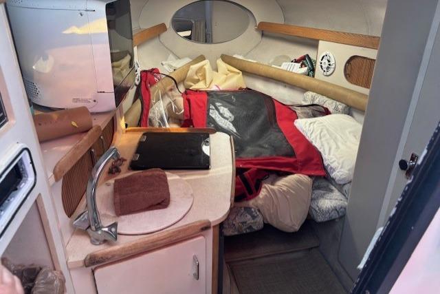 Interior of 2000 Four Winns 238 Vista boat with compact kitchen and cozy sleeping area.