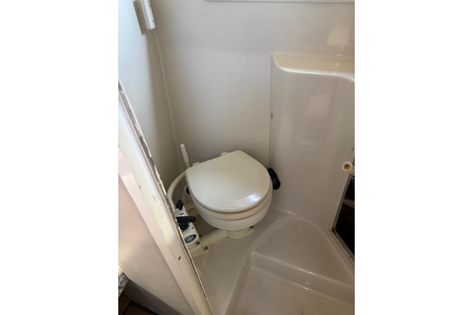 Compact marine toilet in 2000 Four Winns 238 Vista boat bathroom.