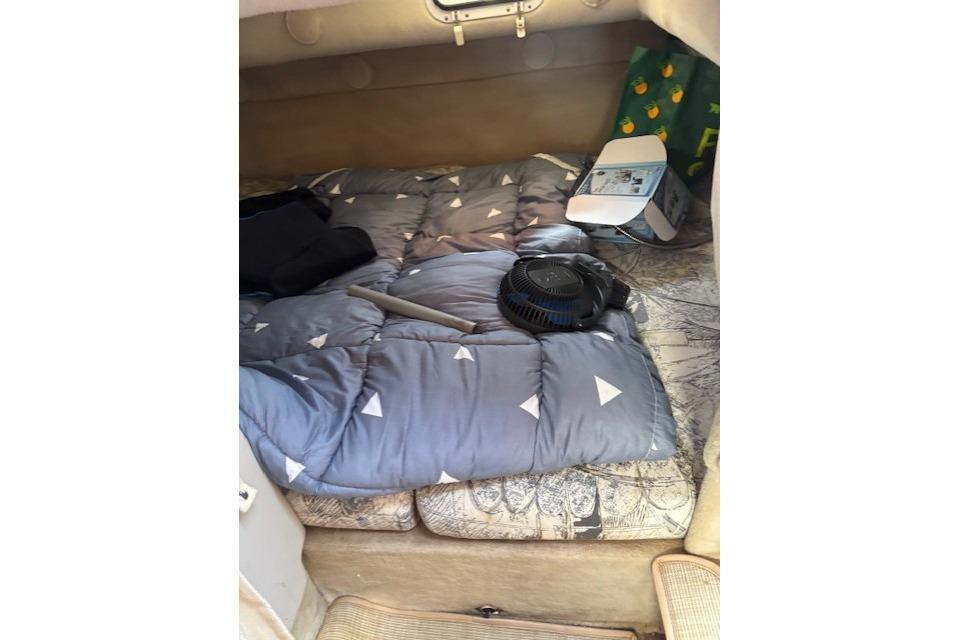 Interior cabin of 2000 Four Winns 238 Vista boat with bedding and fan.