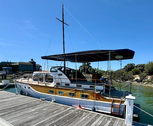 1966 Rampart 48 boat docked, featuring classic wooden design and canopy, under clear blue sky.