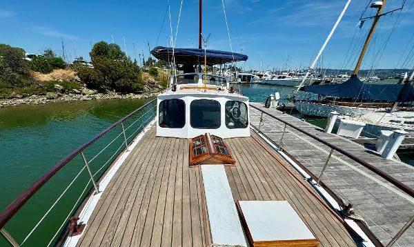 1966 Rampart 48 yacht docked at marina, featuring wooden deck and classic design.