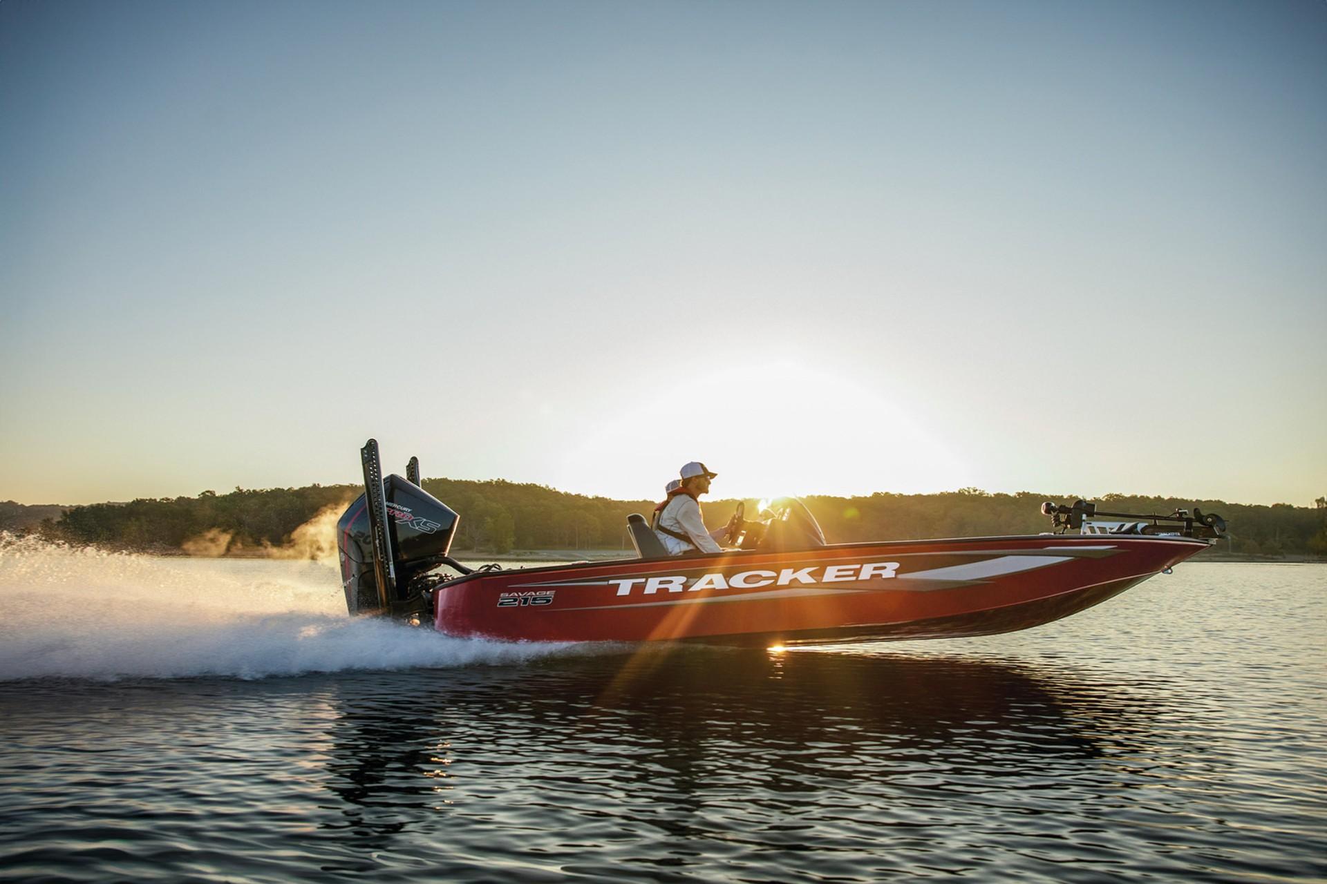 2026 Tracker Savage 215 boat speeding on a lake at sunset.