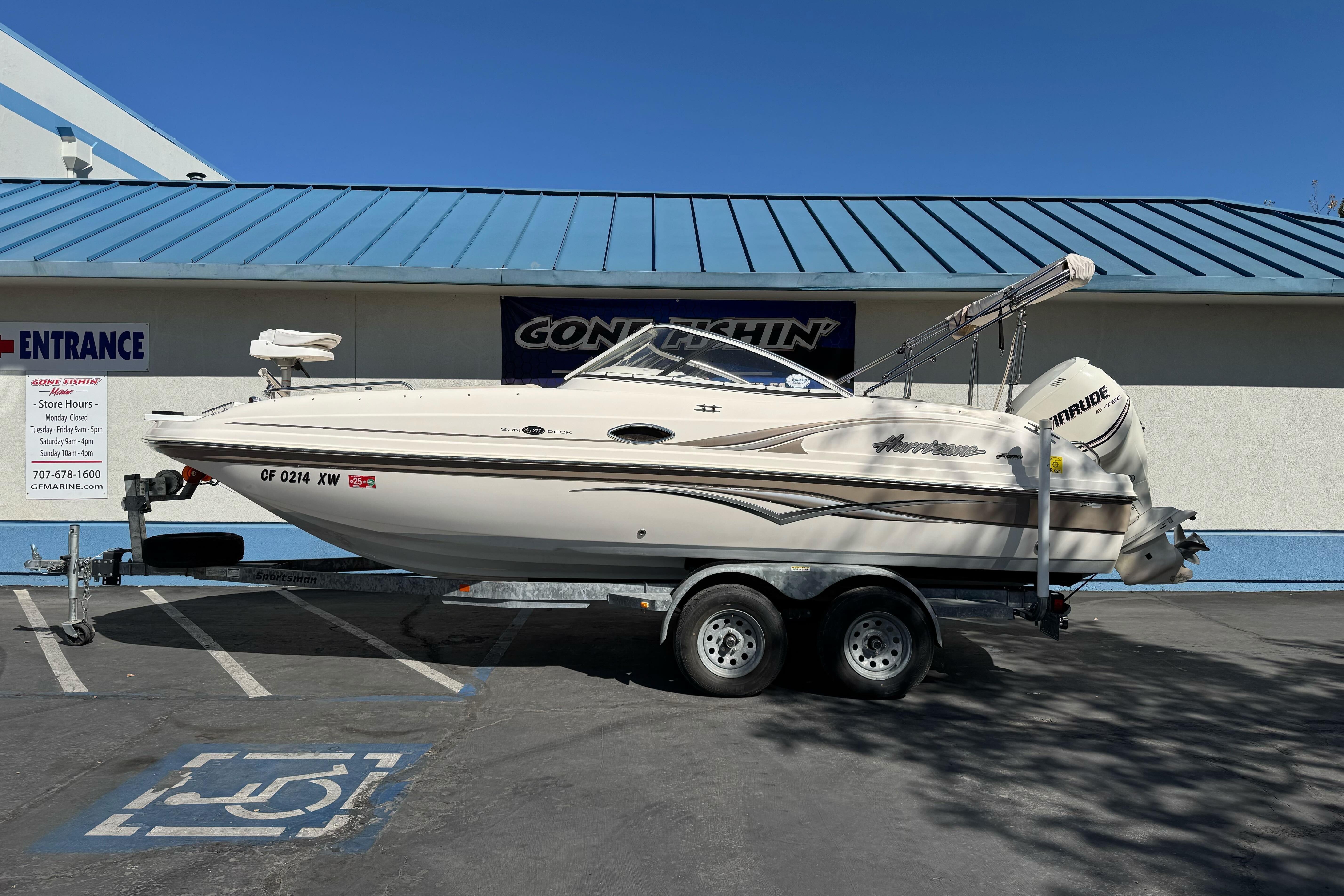 2007 Hurricane SunDeck 217 OB boat on trailer, parked outside a building.