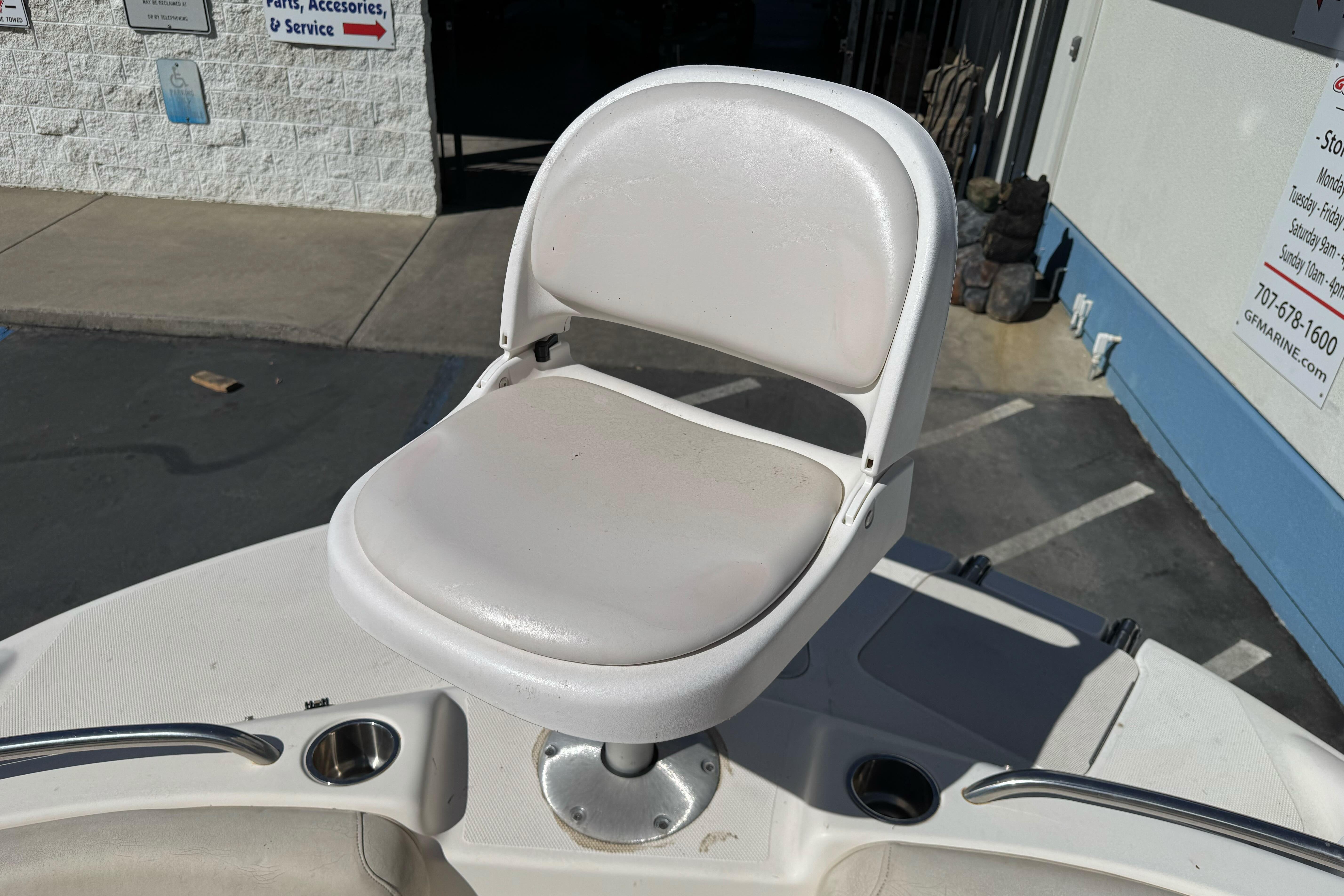 White seat on a 2007 Hurricane SunDeck 217 OB boat, near a marine service shop.