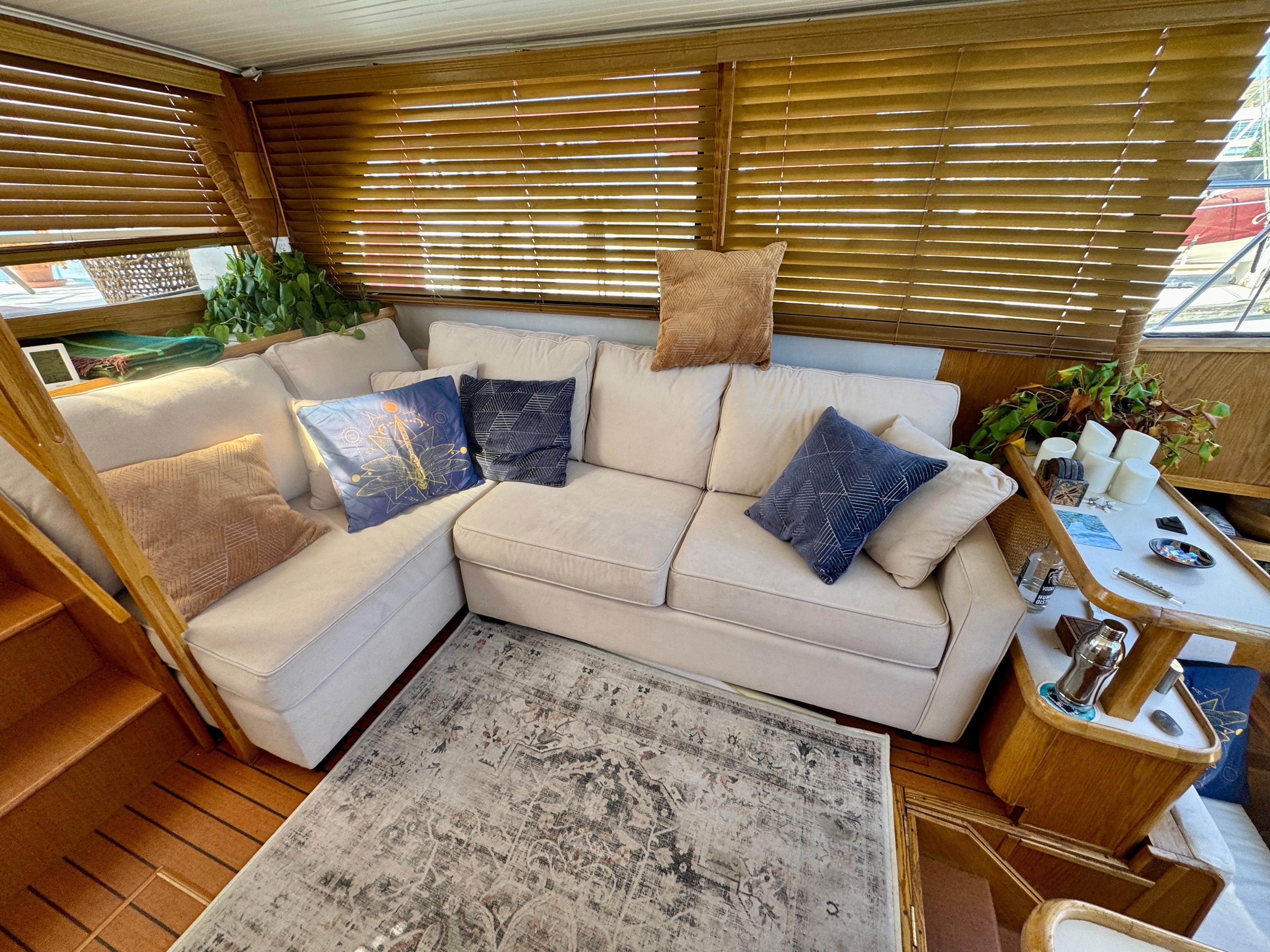 Cozy interior of 1989 Chris-Craft Catalina with white sofa, decorative pillows, and wooden blinds.