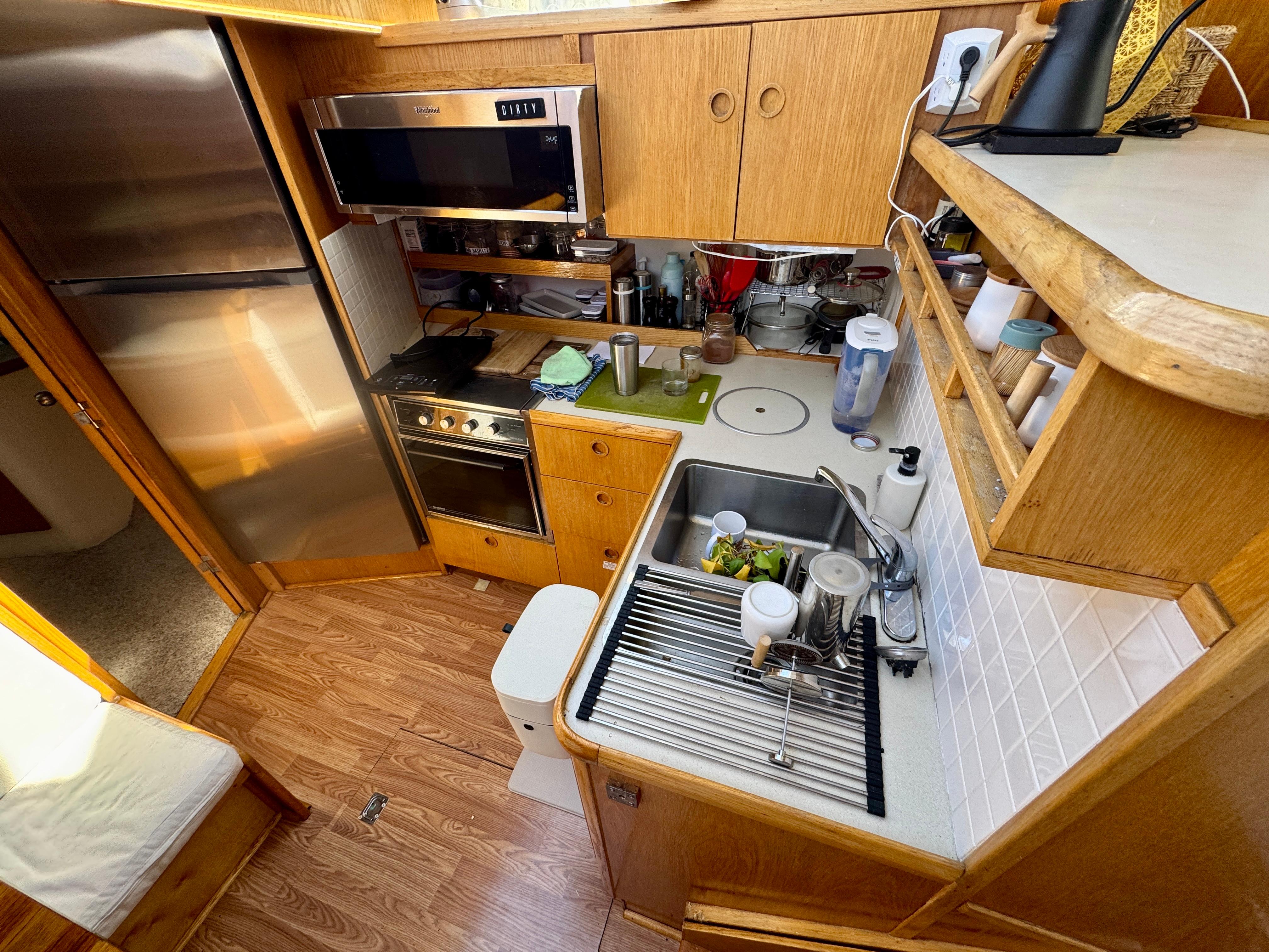 1989 Chris-Craft Catalina boat kitchen with wooden cabinets, stainless steel appliances, and compact design.