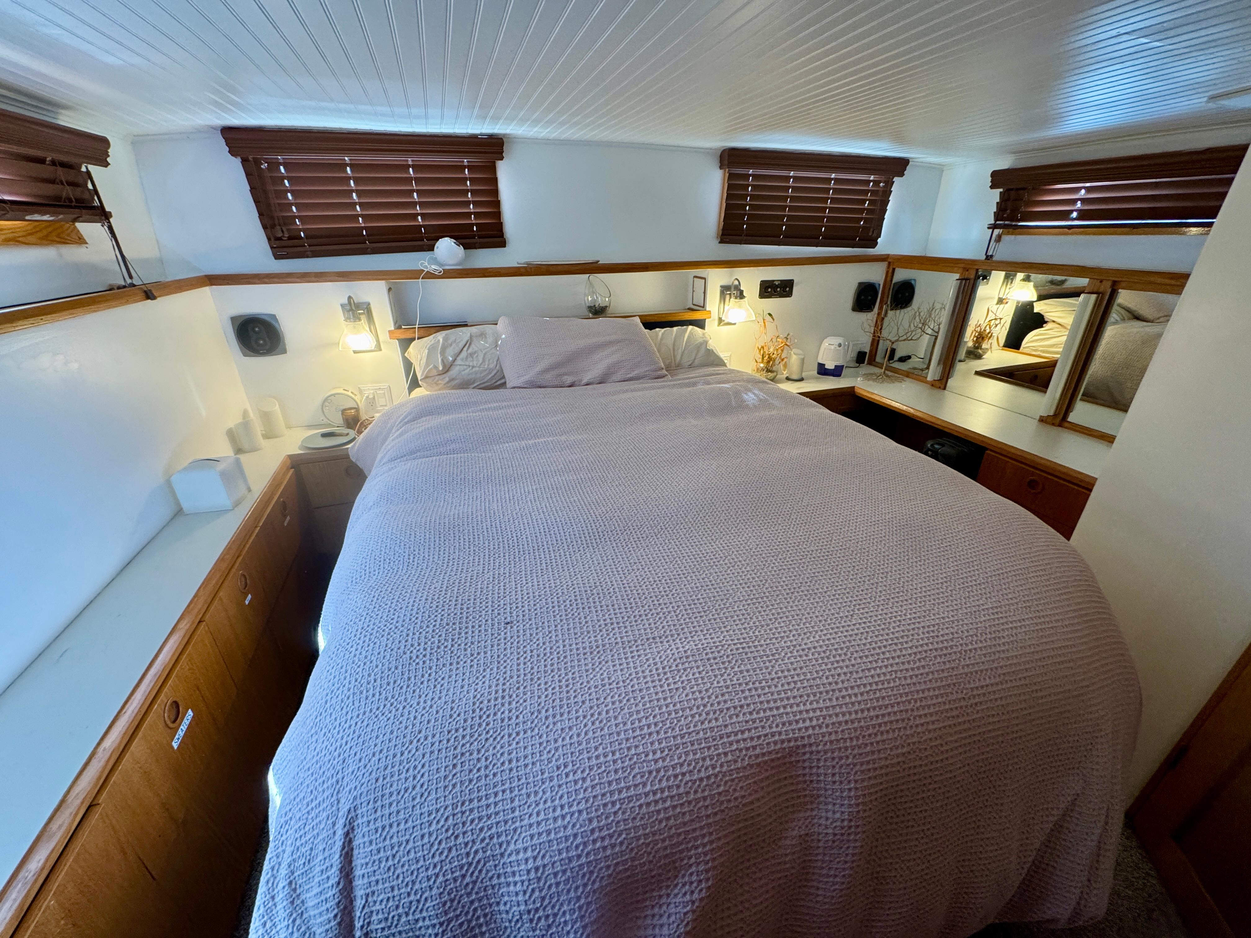 Cozy bedroom interior of 1989 Chris-Craft Catalina boat with wooden accents and soft lighting.