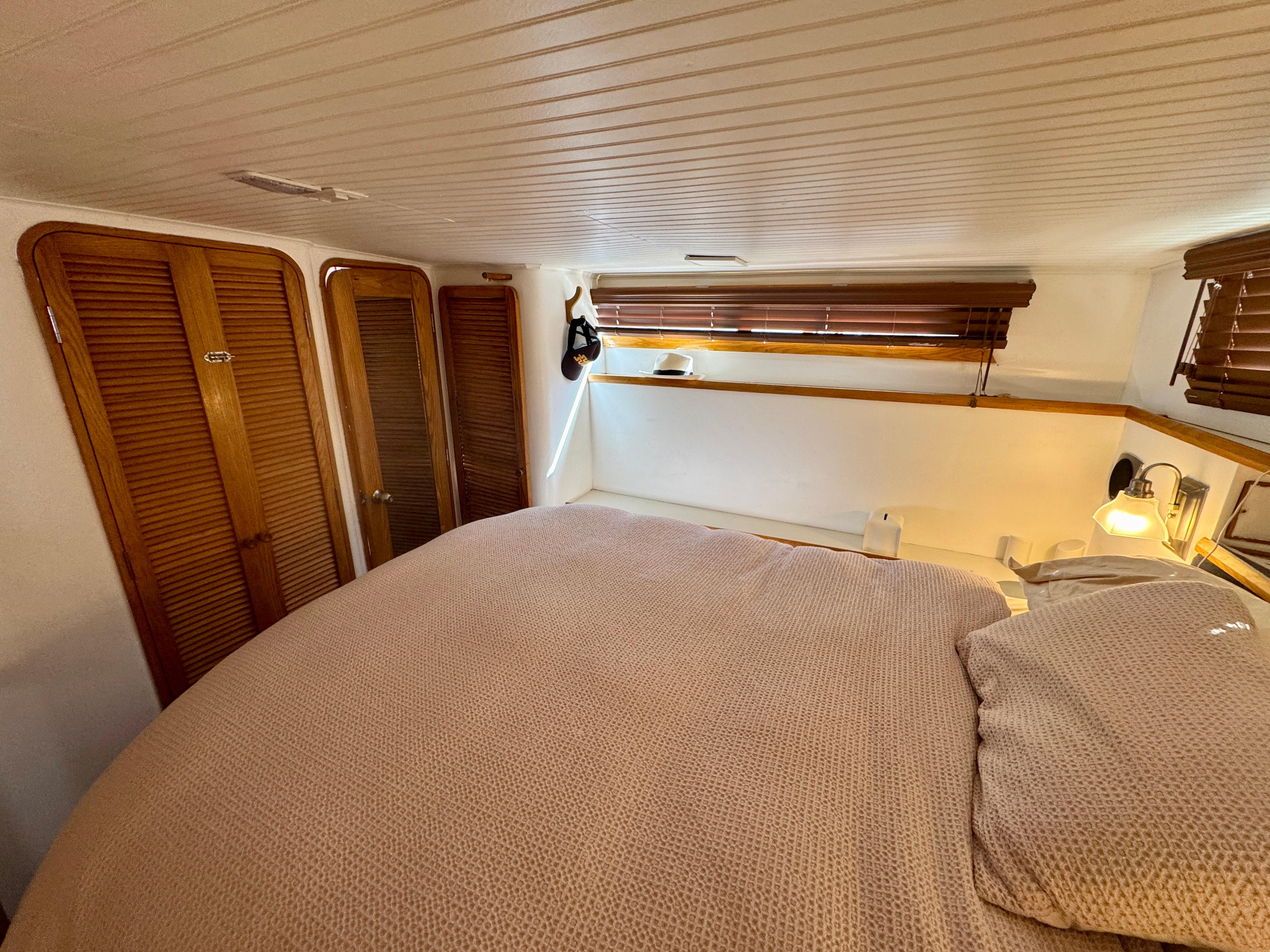 Cozy bedroom interior of 1989 Chris-Craft Catalina boat with wooden accents and soft lighting.