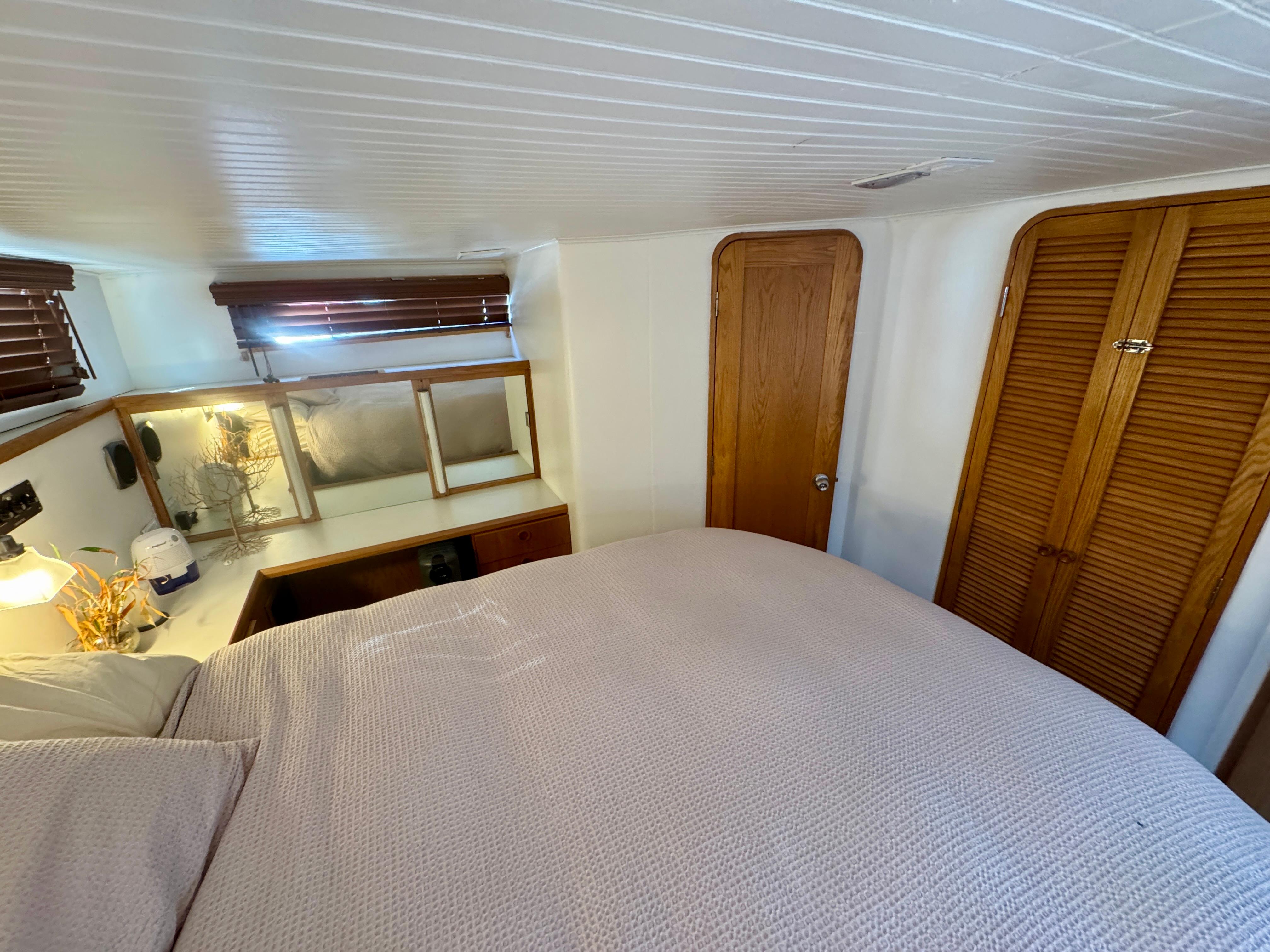 Cozy bedroom interior of 1989 Chris-Craft Catalina boat with wooden accents and soft lighting.