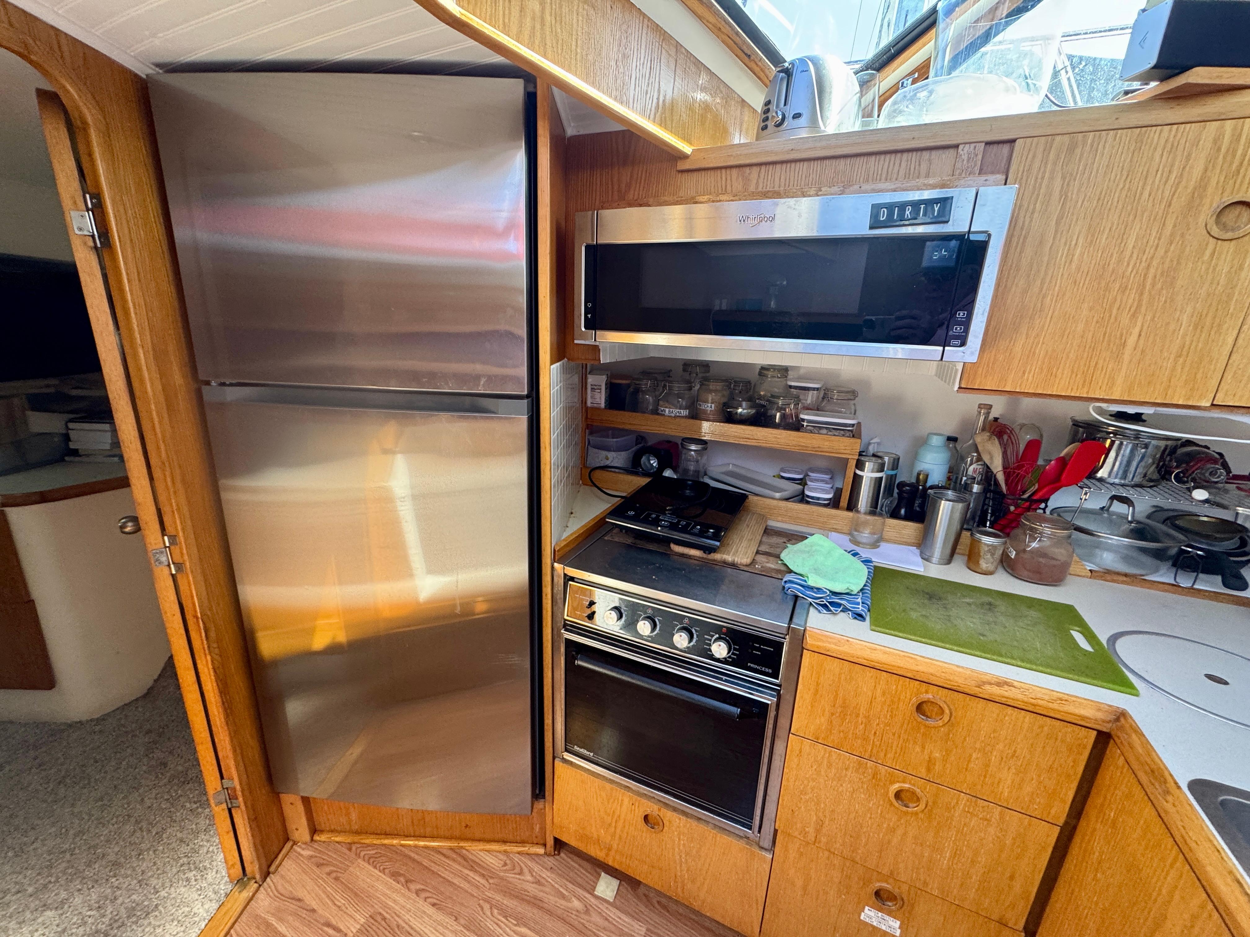 1989 Chris-Craft Catalina kitchen with stainless steel appliances and wooden cabinetry.