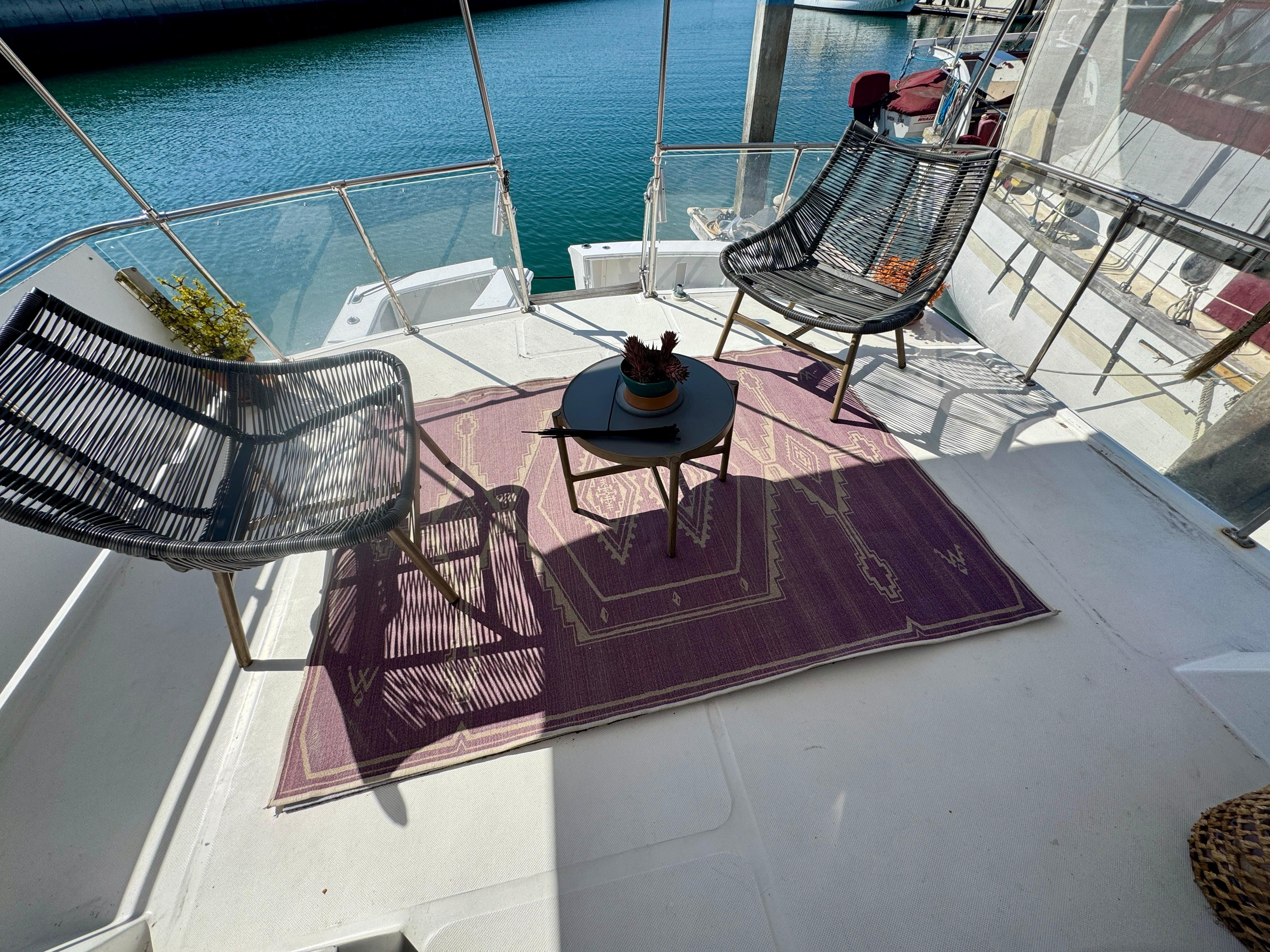 1989 Chris-Craft Catalina boat deck with chairs, table, and purple rug by the water.