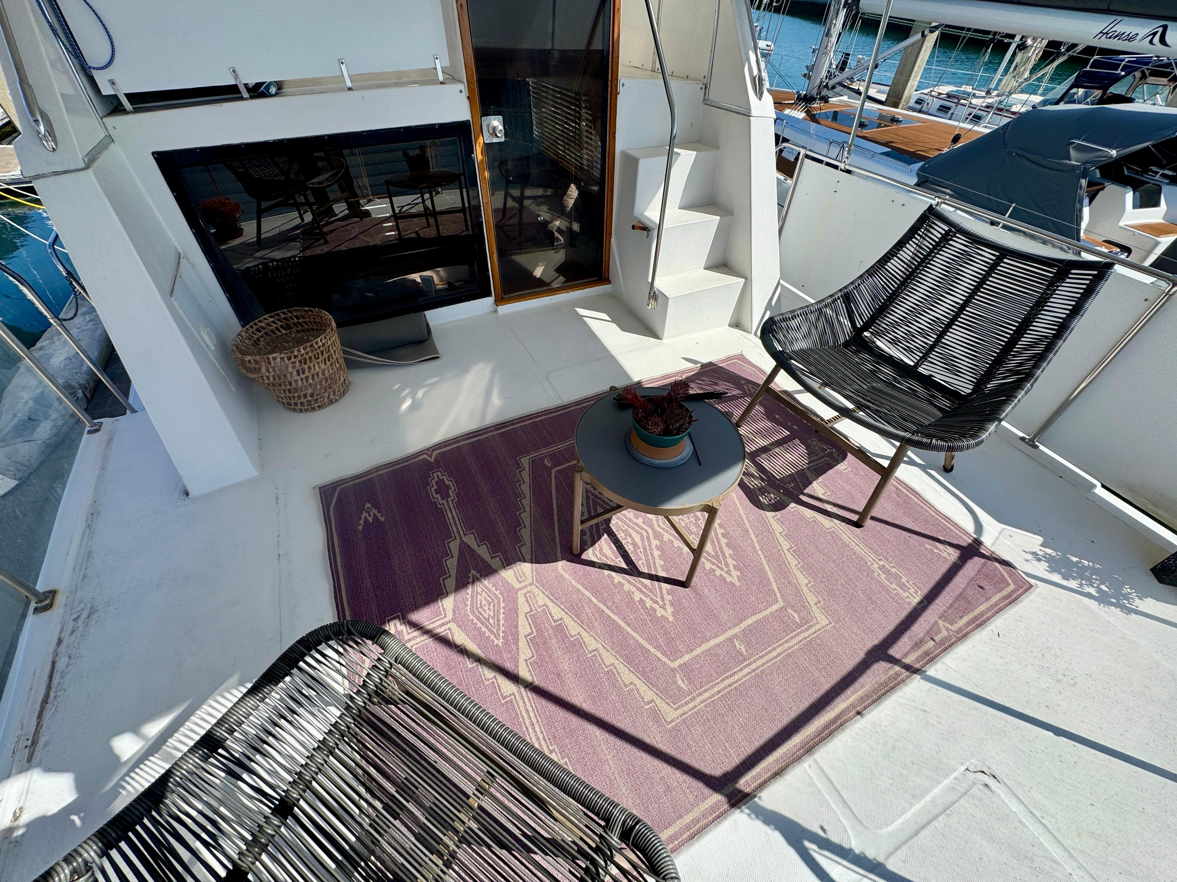 1989 Chris-Craft Catalina boat deck with chairs, table, and decorative rug.