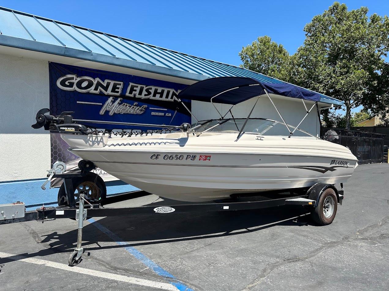 2001 Larson SEi 190 boat on trailer, parked outside a marine shop.
