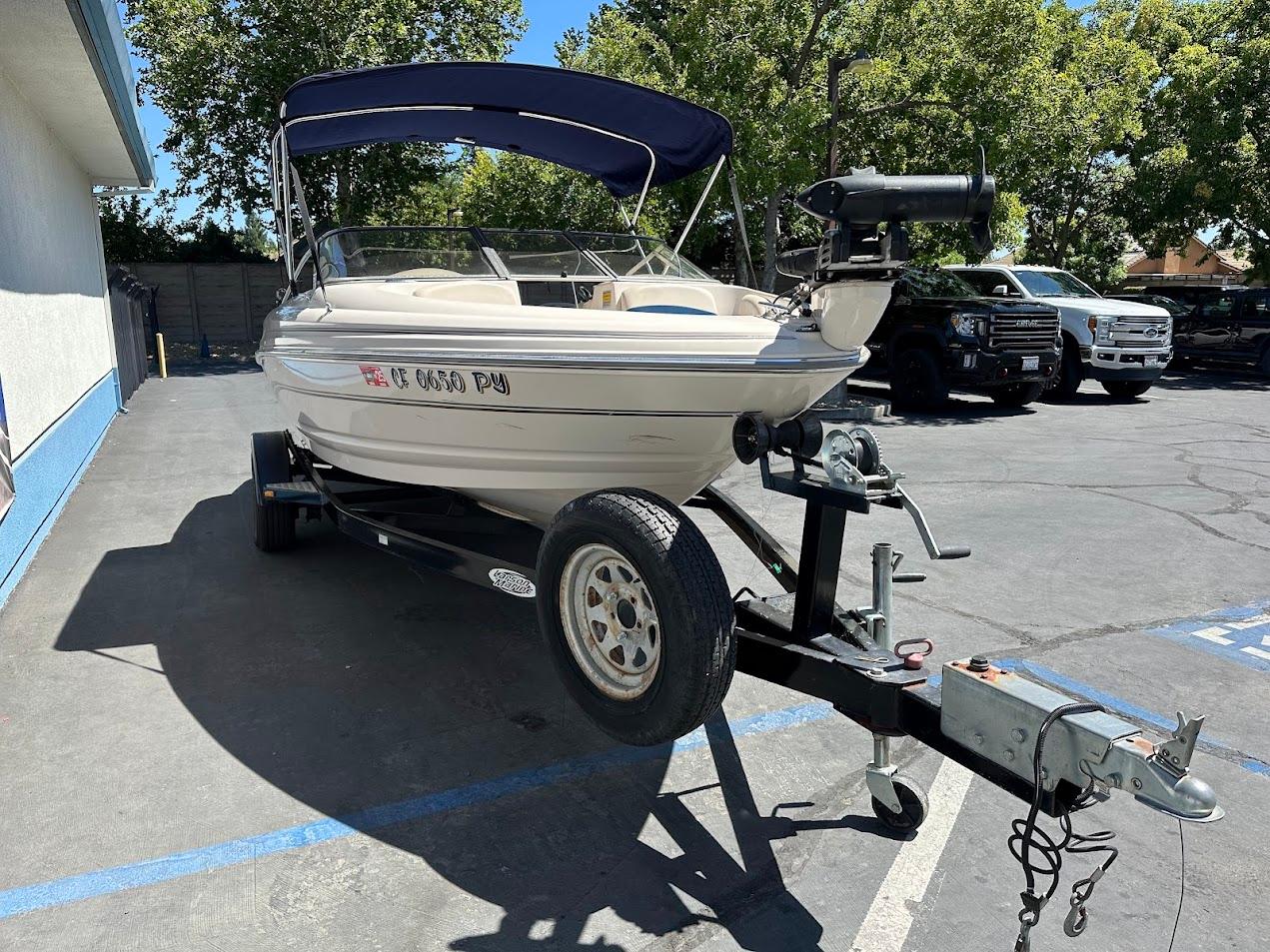 2001 Larson SEi 190 boat on trailer, parked outdoors with trees and vehicles in the background.
