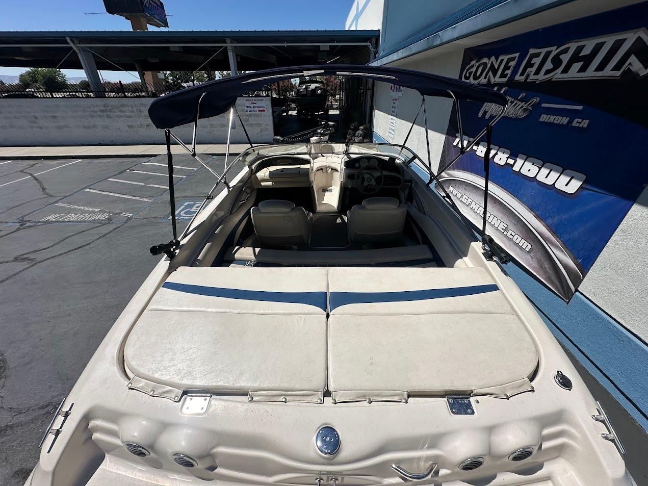 2001 Larson SEi 190 boat with canopy, parked near a blue building.