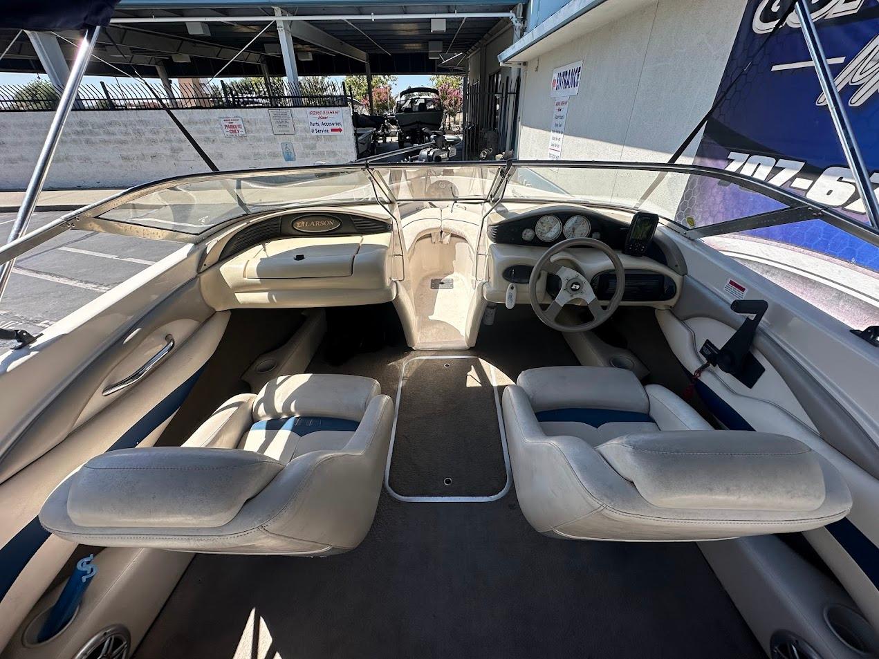 Interior of a 2001 Larson SEi 190 boat, featuring beige seating and steering console.
