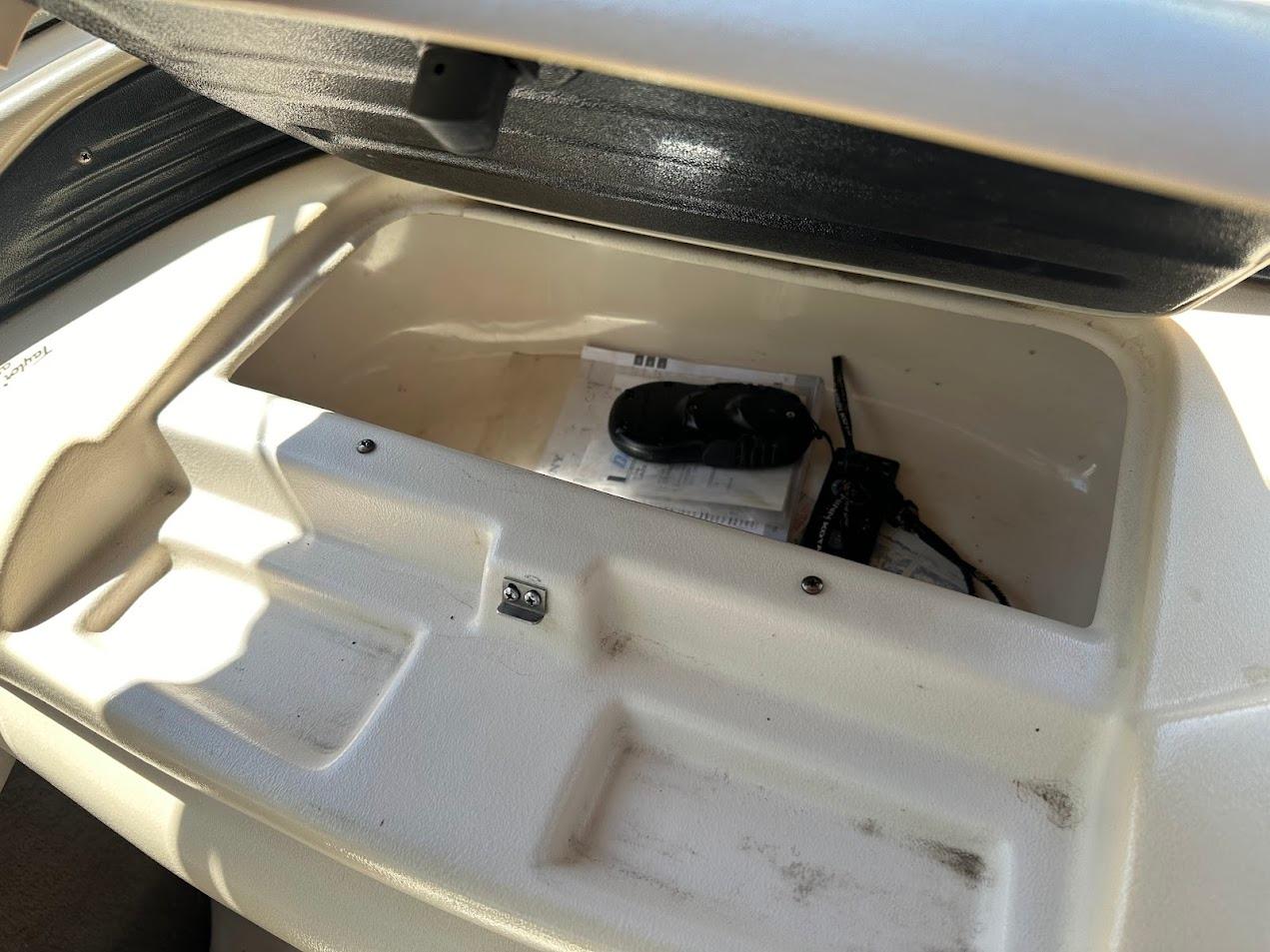 Open storage compartment in a 2001 Larson SEi 190 boat, containing documents and a device.