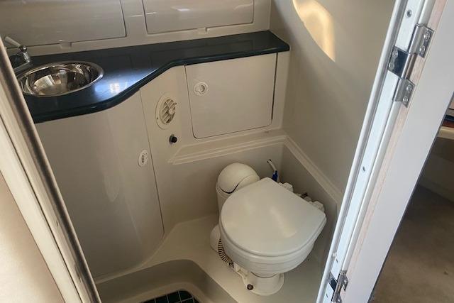 Compact bathroom in a 1995 Regal 402 boat, featuring a toilet and sink.