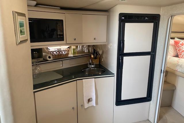Compact kitchen area in a 1995 Regal 402 boat with sink, microwave, and fridge.
