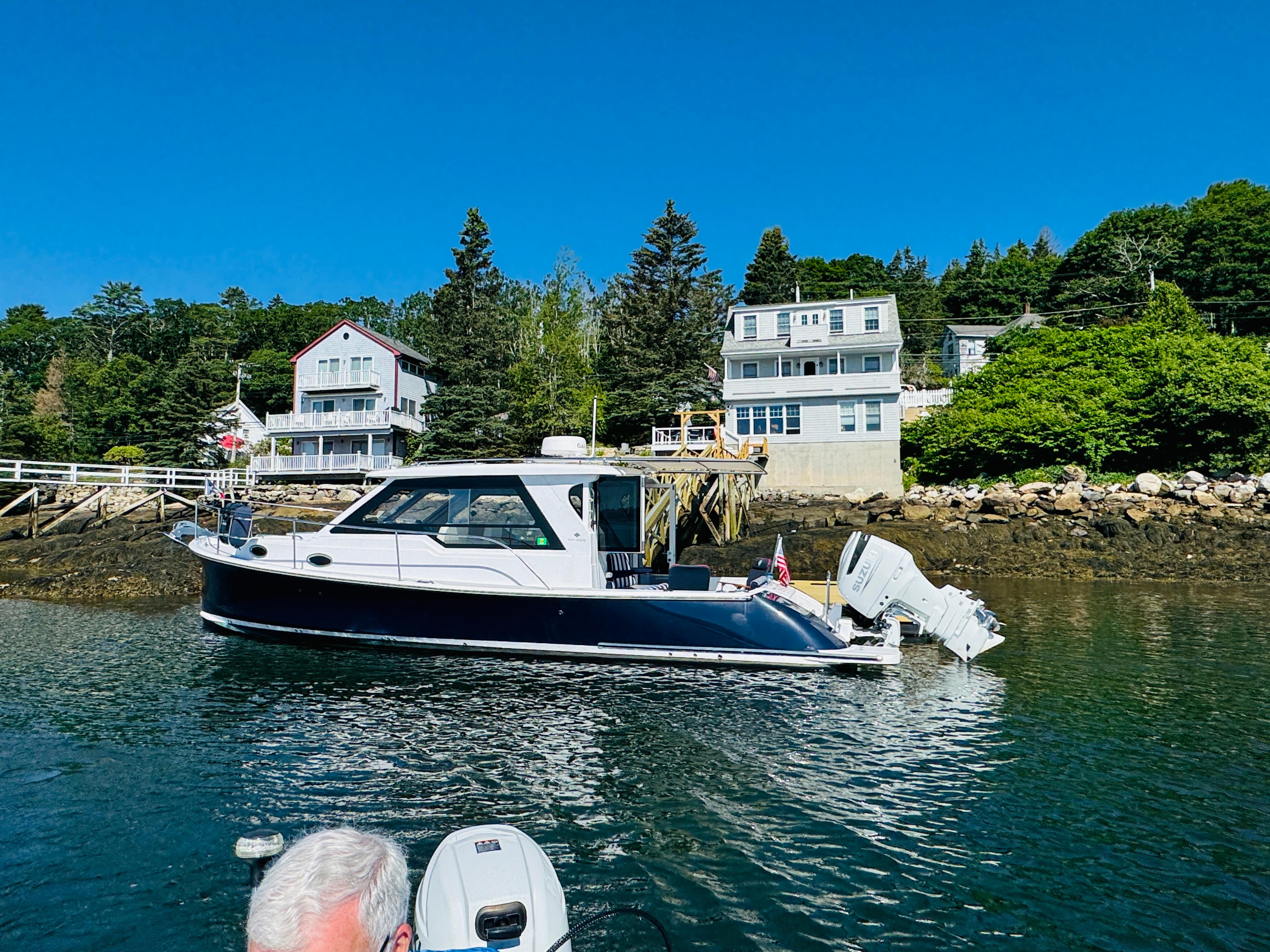 2024 True North 34 Outboard Express boat docked near waterfront homes.