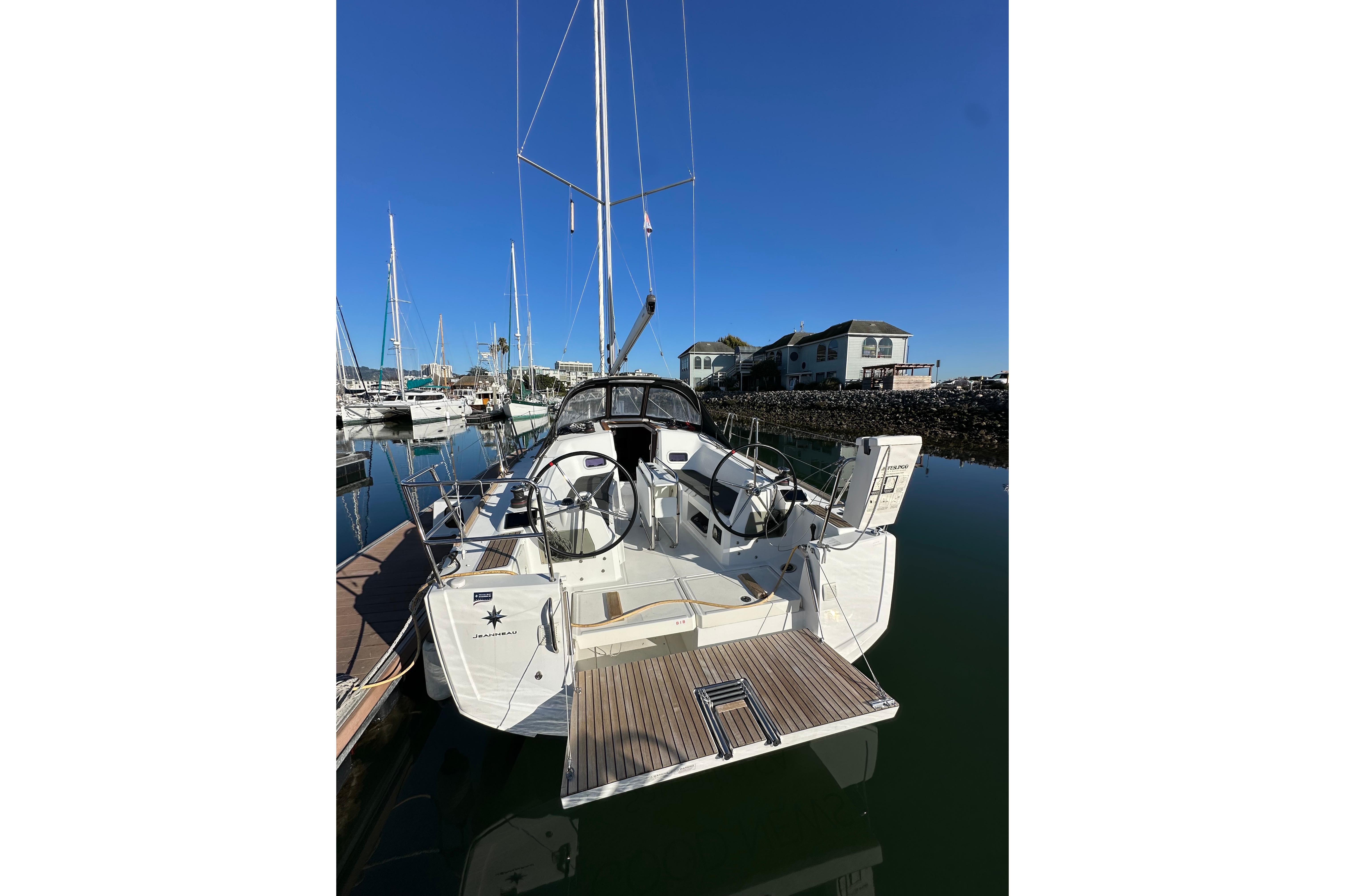 2021 Jeanneau Sun Odyssey 349 sailboat docked in a marina under clear blue skies.