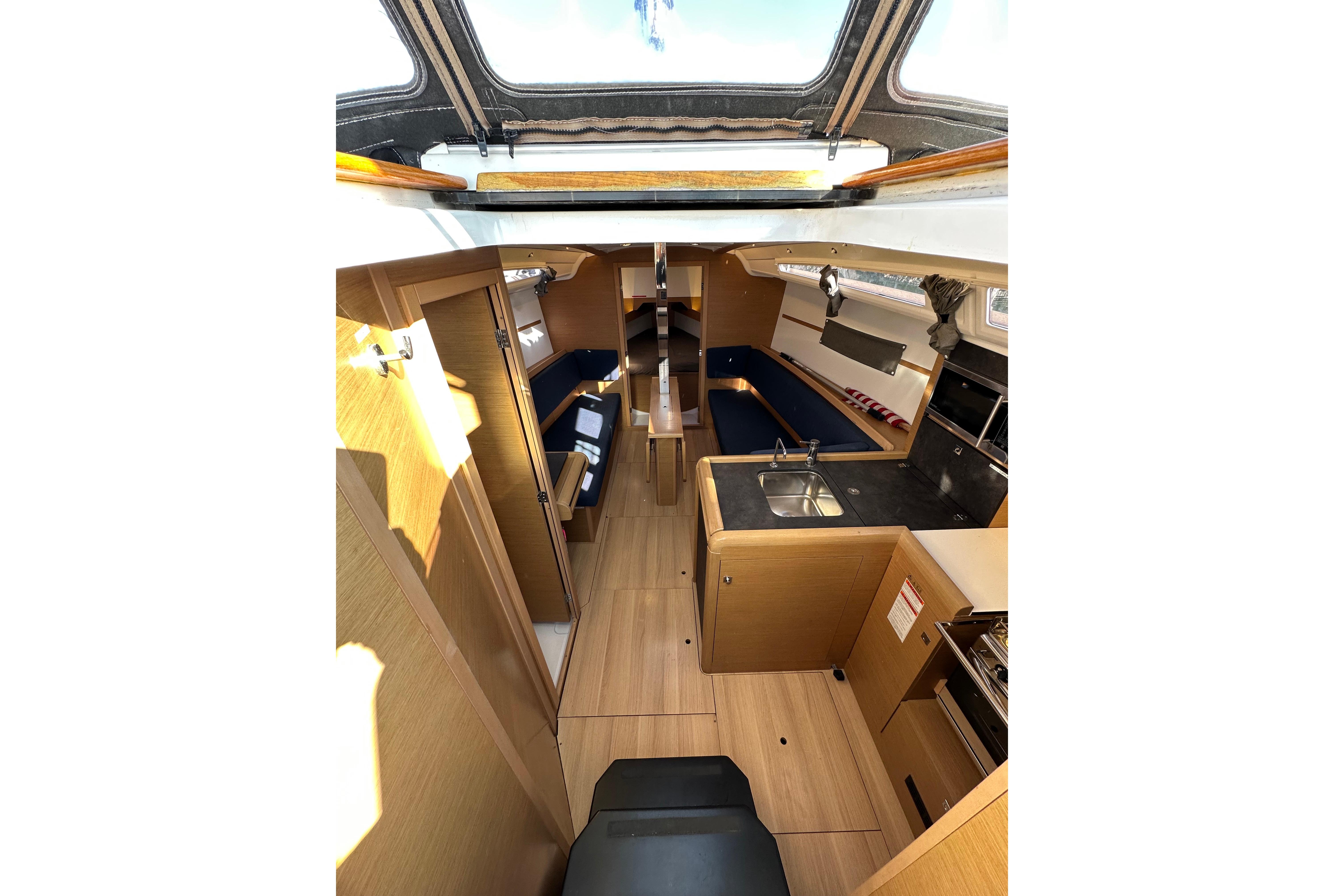 Interior of 2021 Jeanneau Sun Odyssey 349 sailboat, featuring modern wood finish and compact kitchen.