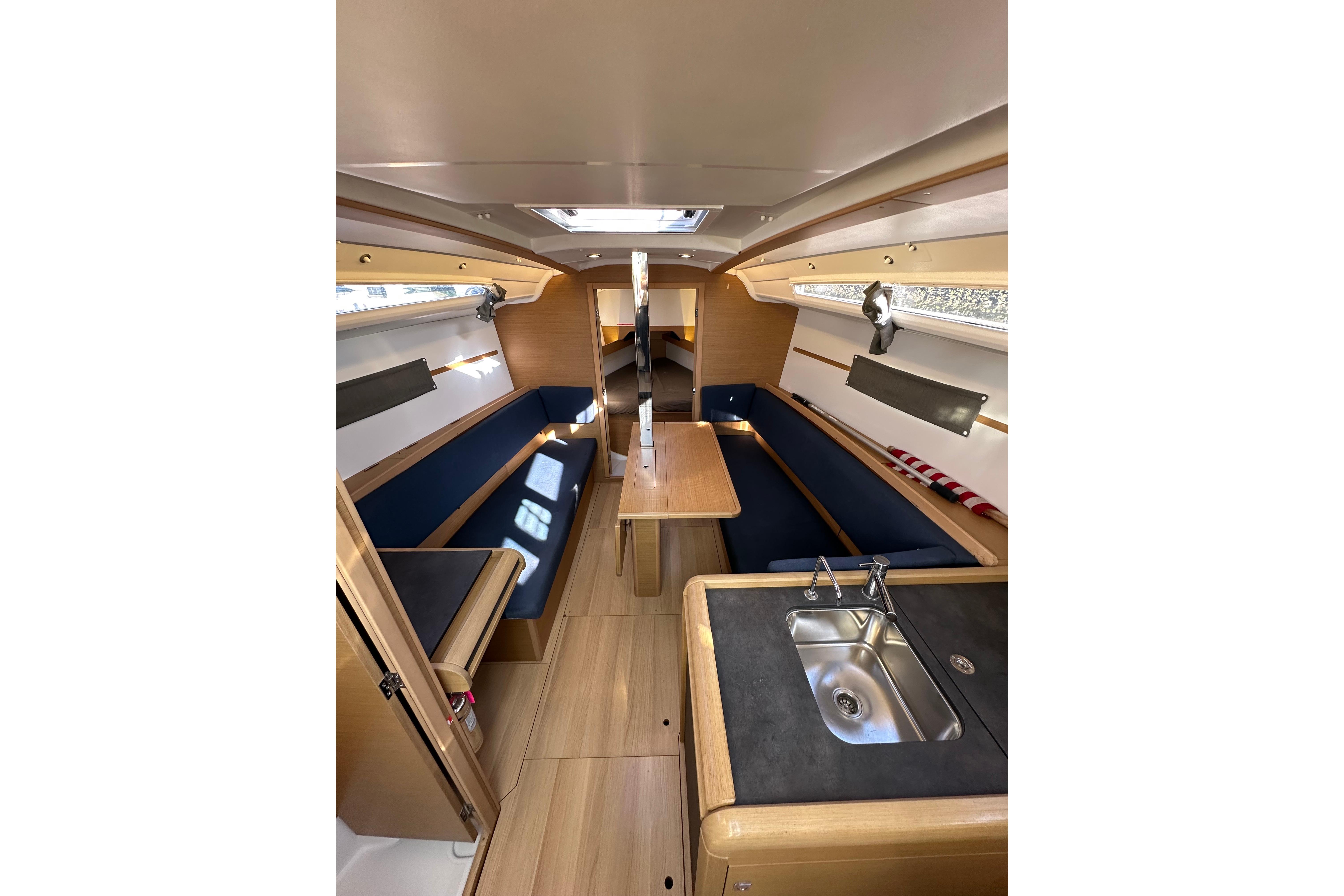 Interior of 2021 Jeanneau Sun Odyssey 349 sailboat, featuring modern wood finish and compact kitchen.