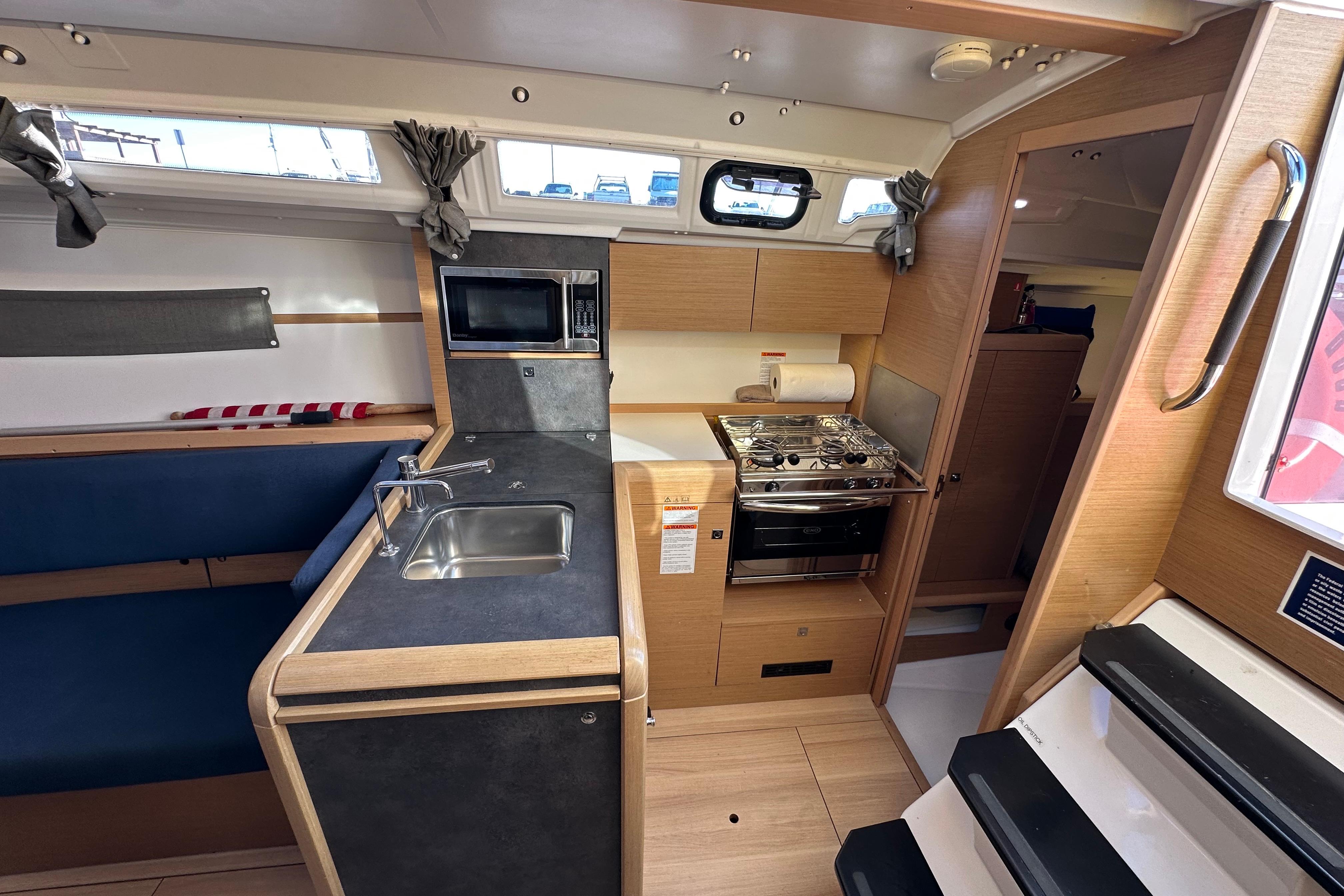 Interior of 2021 Jeanneau Sun Odyssey 349 sailboat, featuring a compact kitchen with sink and stove.