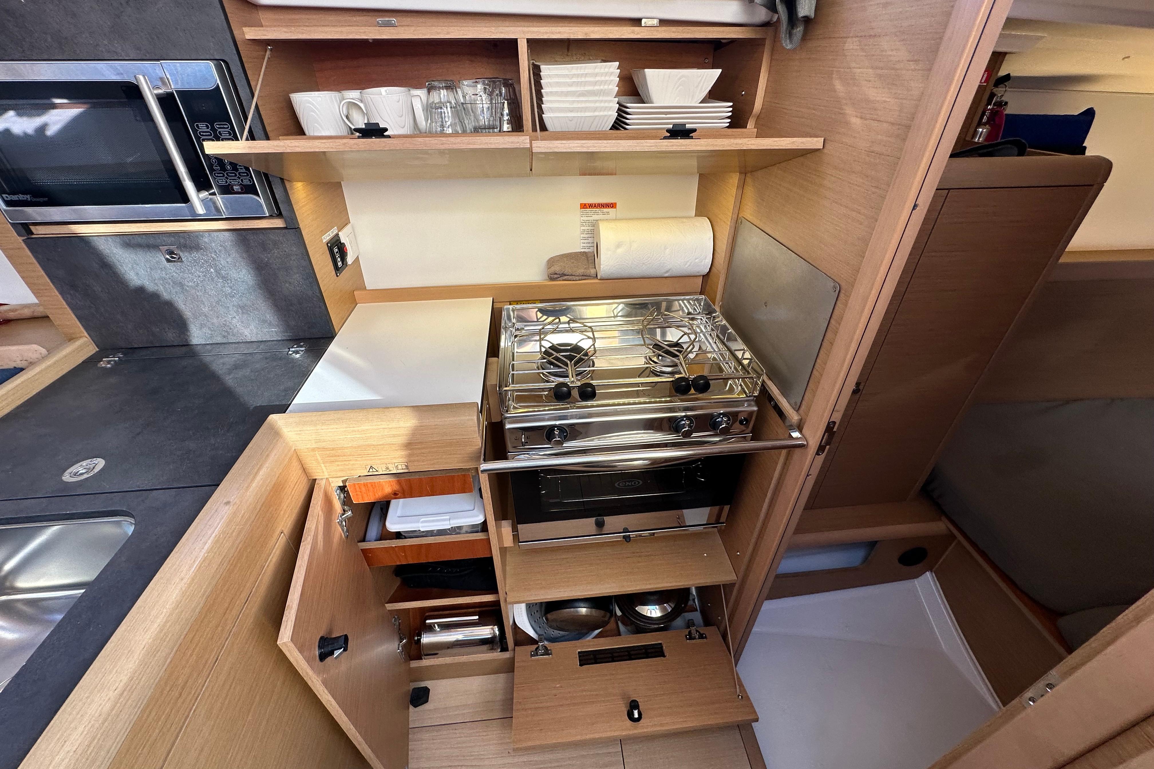 Modern kitchen in 2021 Jeanneau Sun Odyssey 349 yacht with stove and storage.