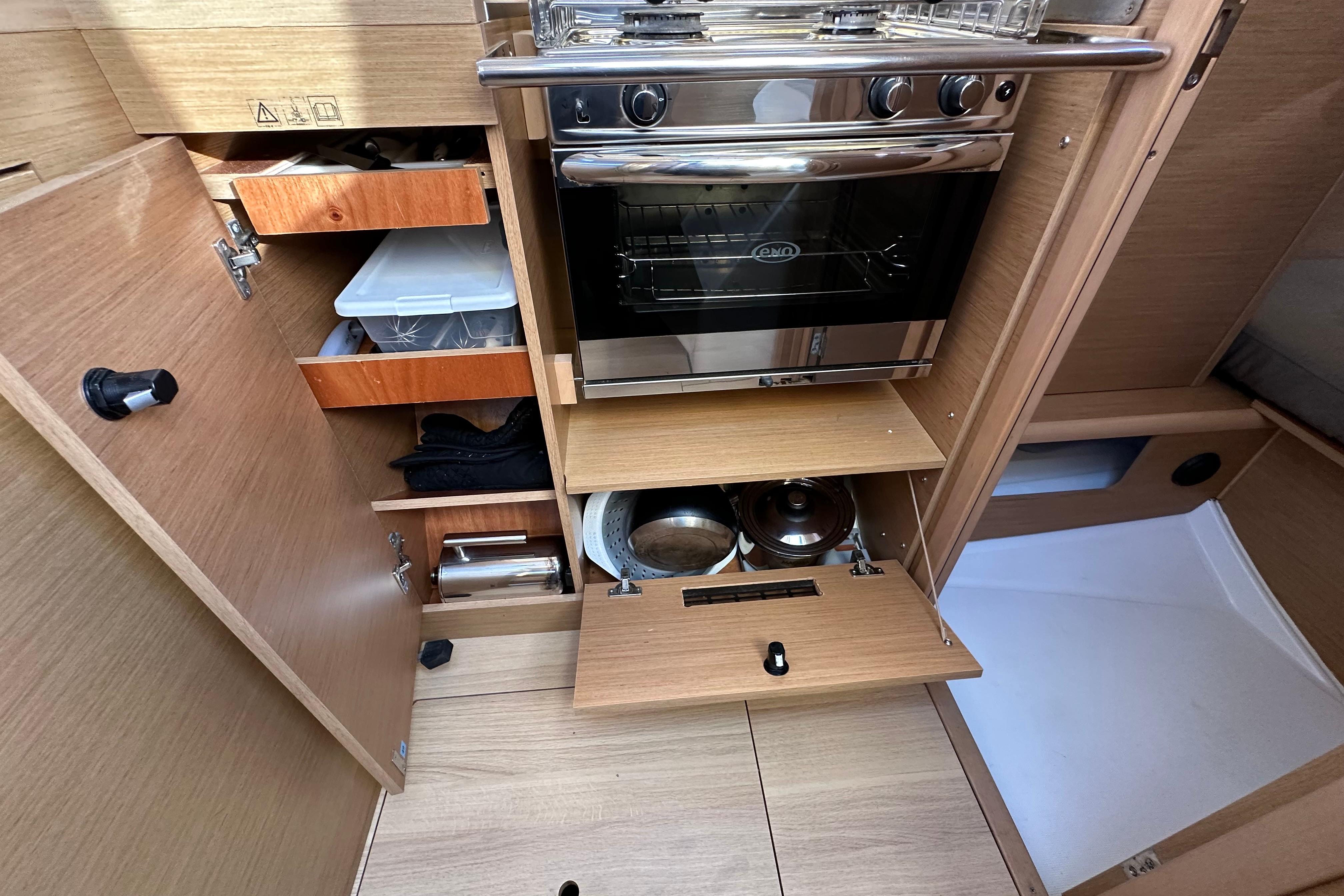 Interior of 2021 Jeanneau Sun Odyssey 349 yacht kitchen with stove and storage.