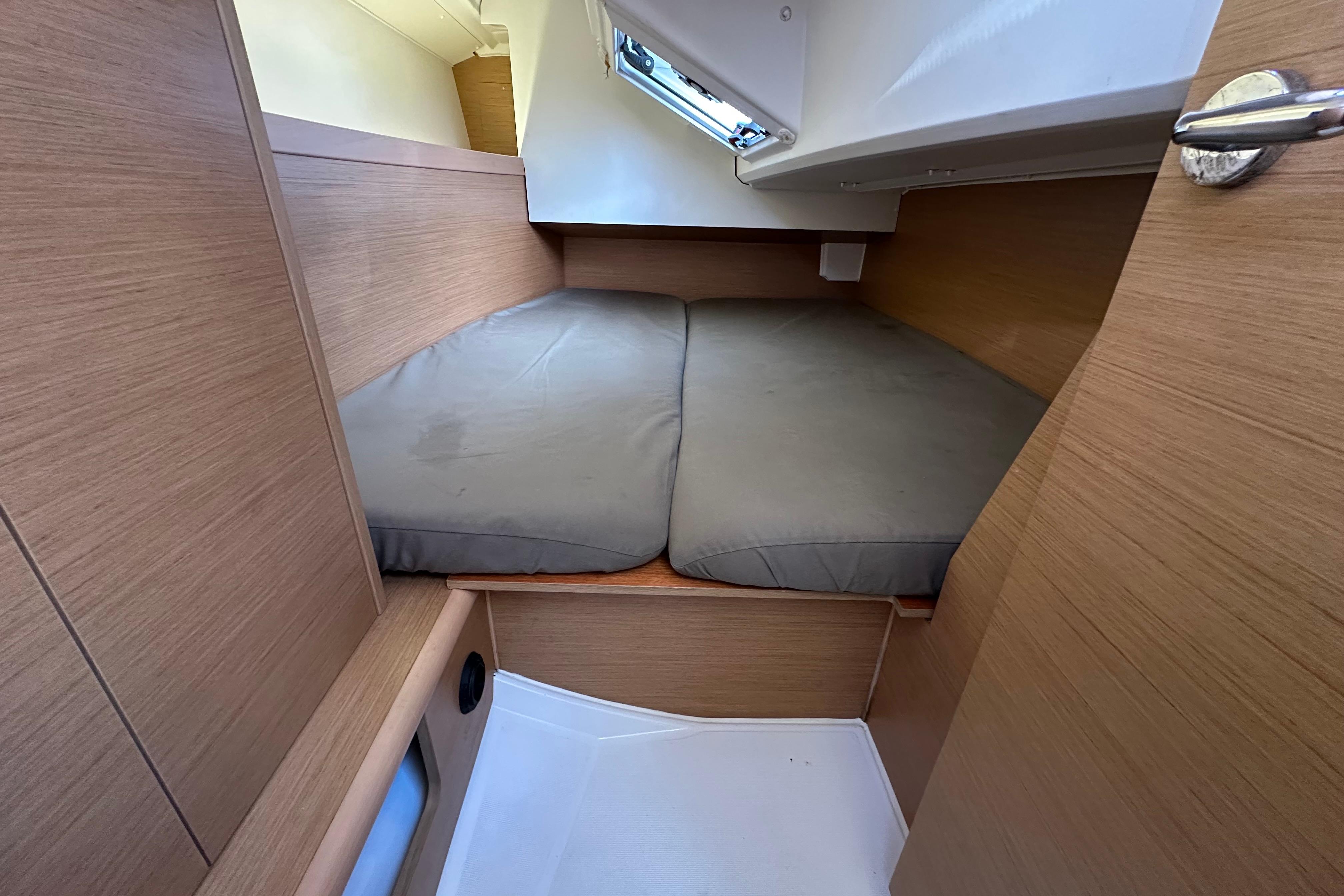 Cozy cabin interior of 2021 Jeanneau Sun Odyssey 349 sailboat with cushioned bed.