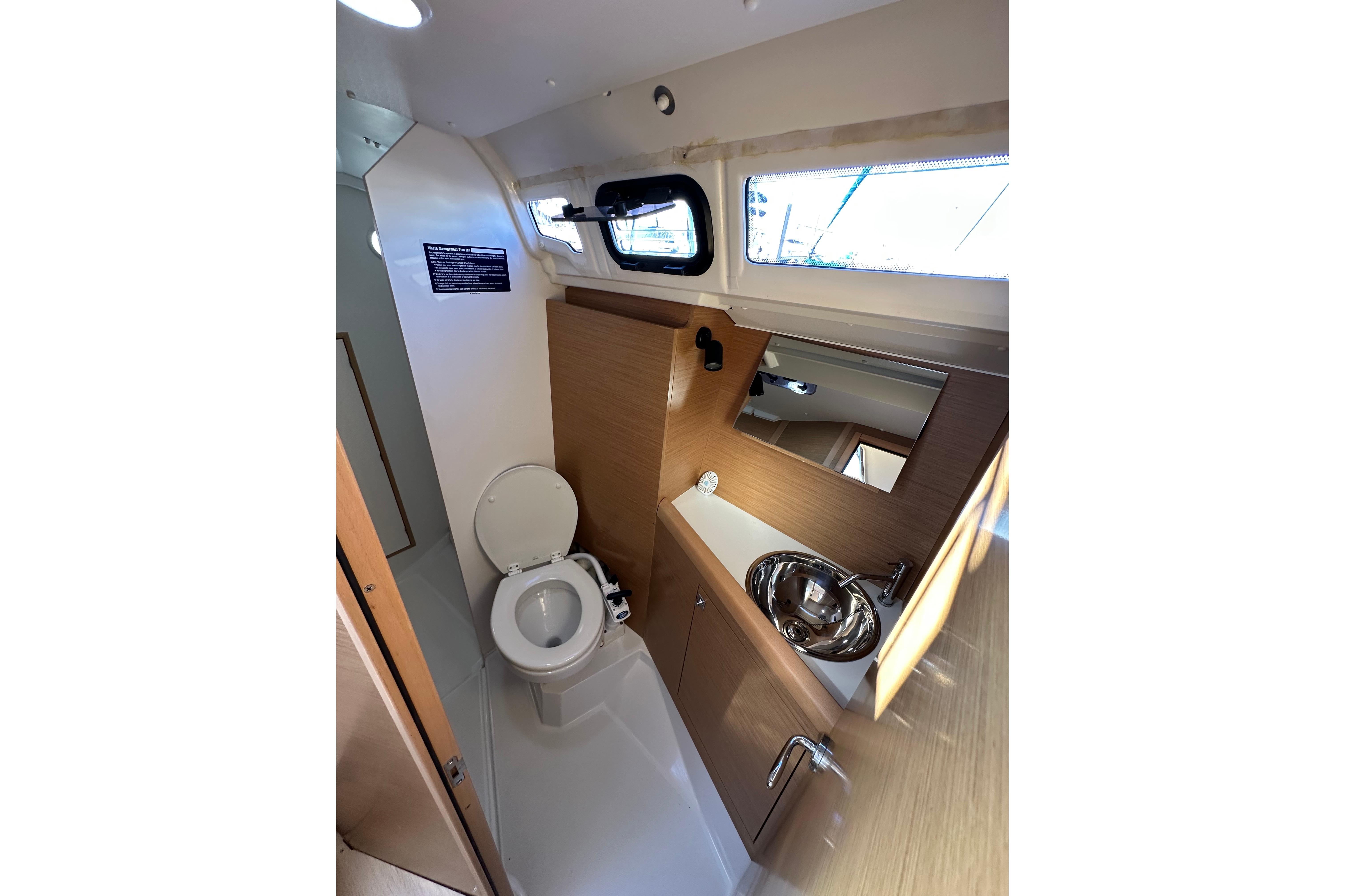 2021 Jeanneau Sun Odyssey 349 yacht bathroom with toilet, sink, and mirror.