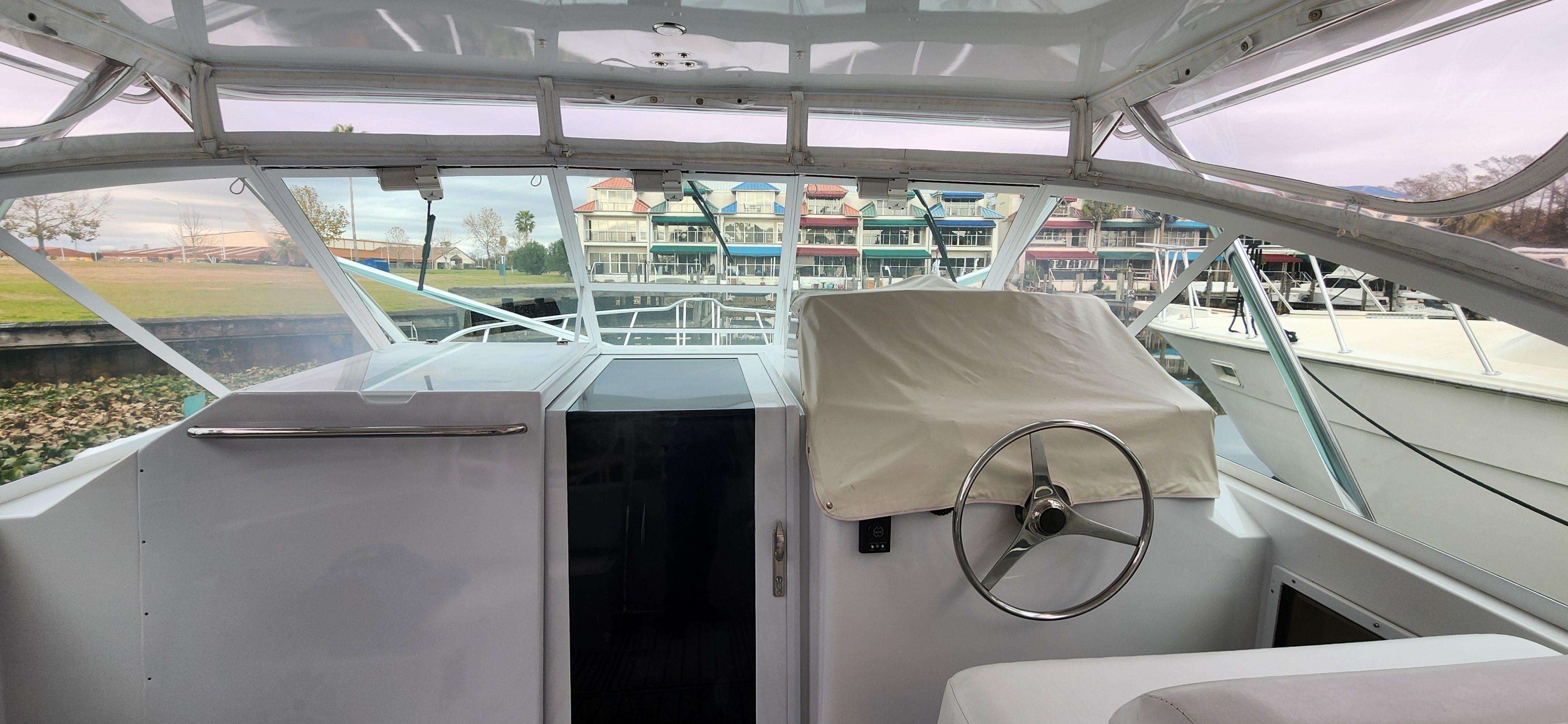 Cabo-35 Express 1995 -AL-US-1995 Cabo 35 Express boat interior with covered steering wheel, docked near colorful buildings.-9547451 | Thumbnail