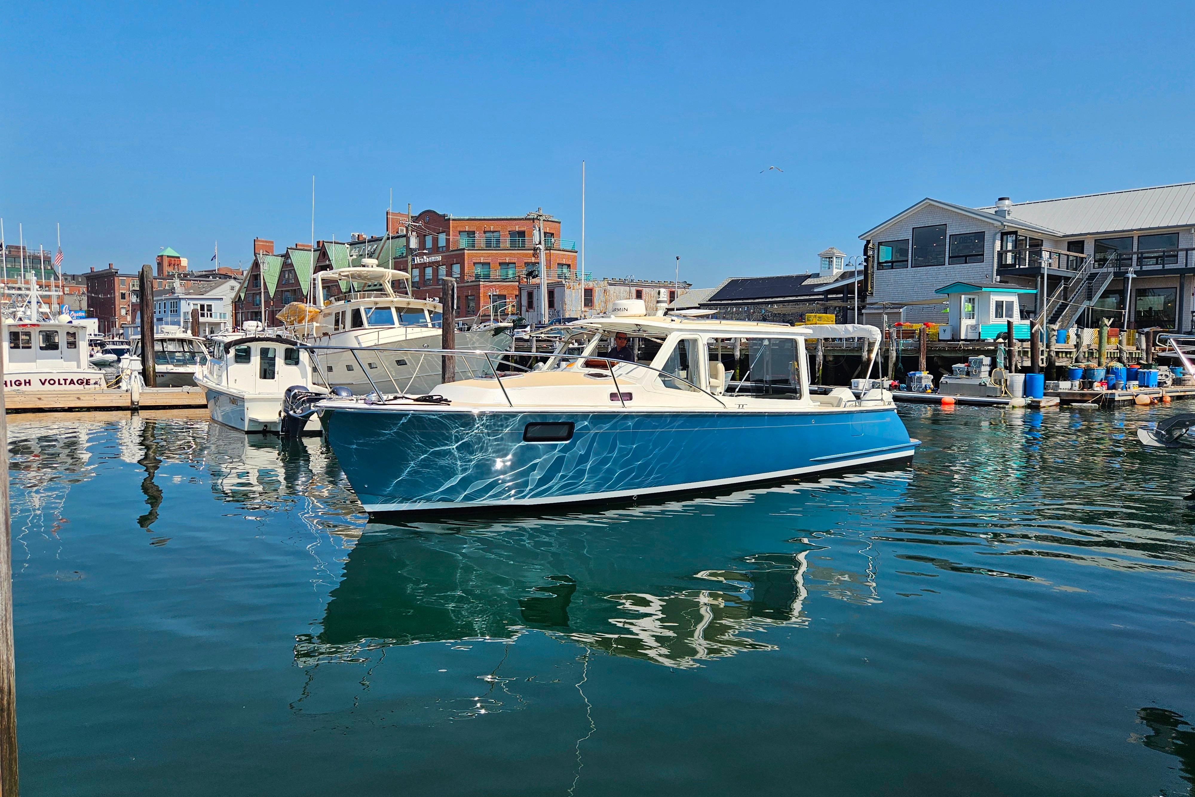 2023 MJM 35 boat docked in a vibrant marina under clear blue skies.