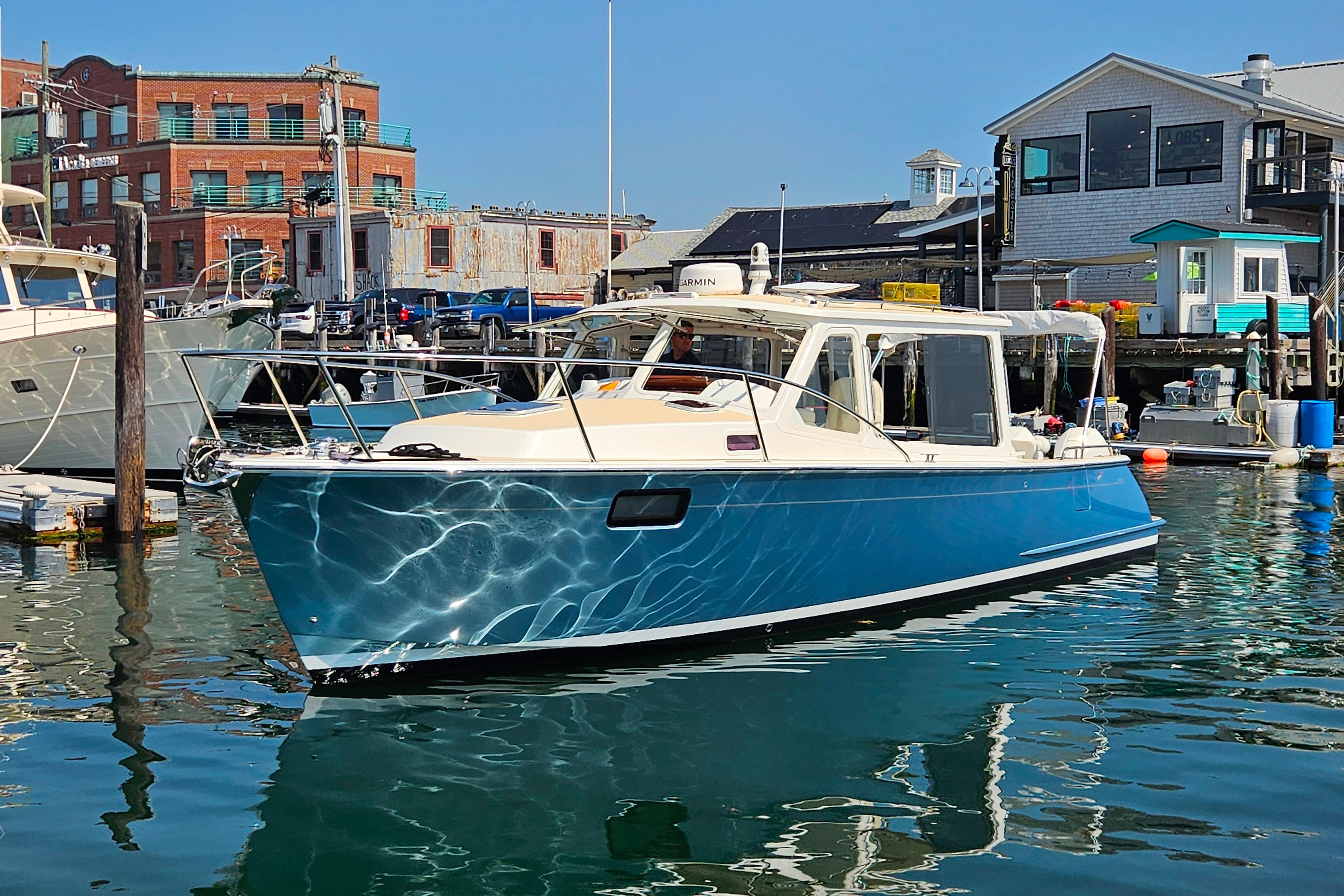 2023 MJM 35 boat docked in a marina with waterfront buildings.