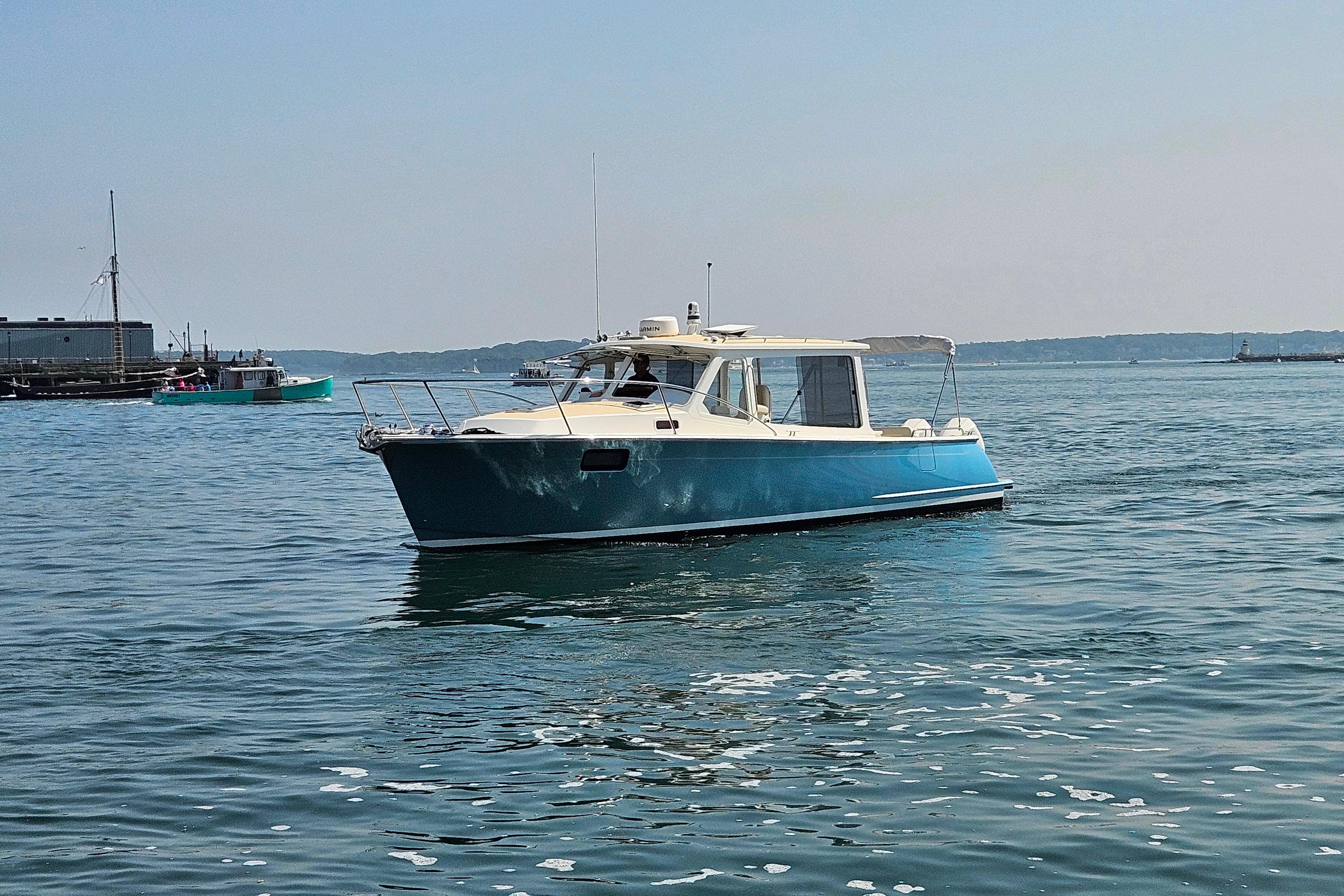 2023 MJM 35 boat cruising on calm waters near a harbor.