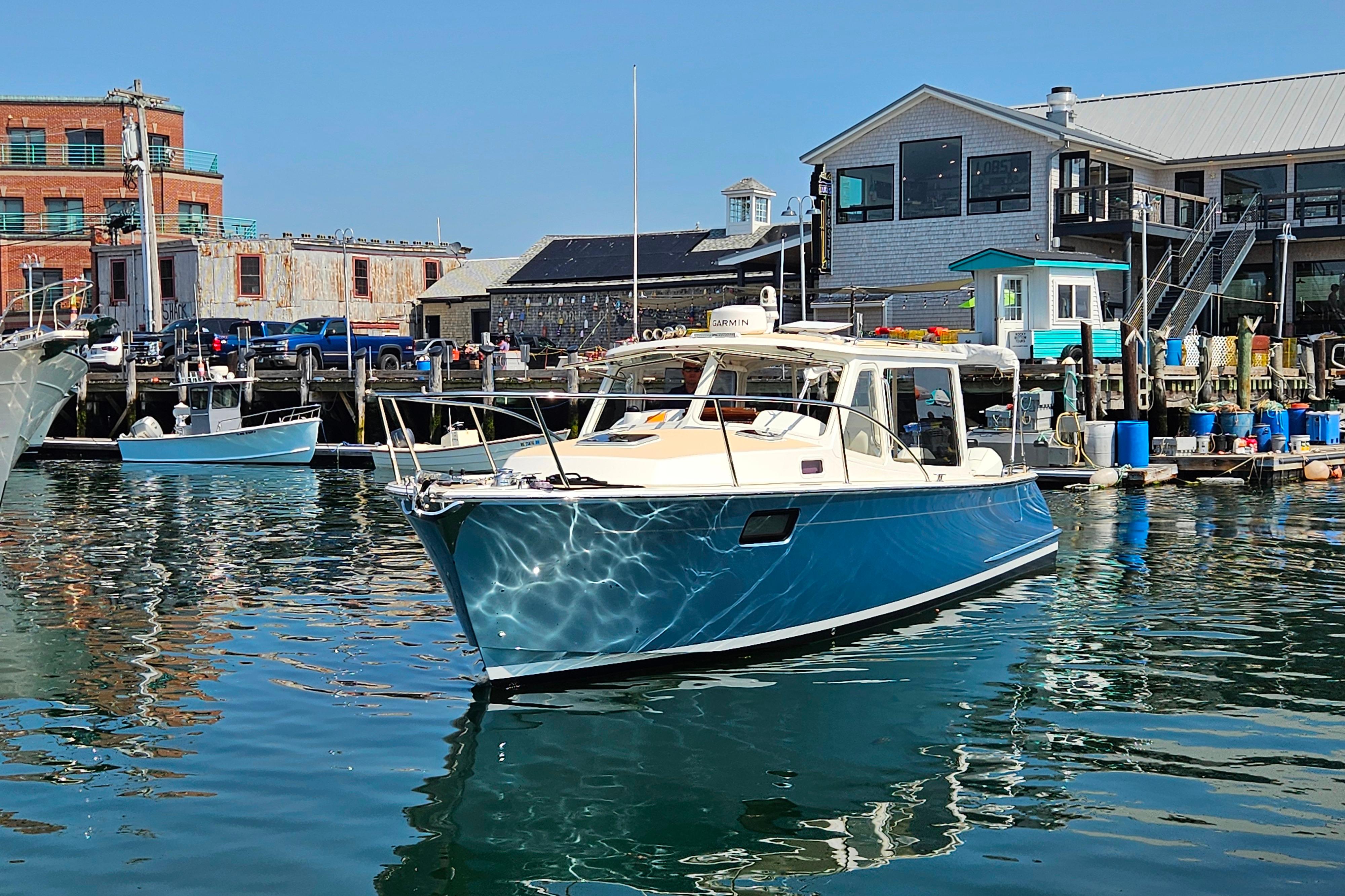 2023 MJM 35 boat docked at a marina with waterfront buildings in the background.
