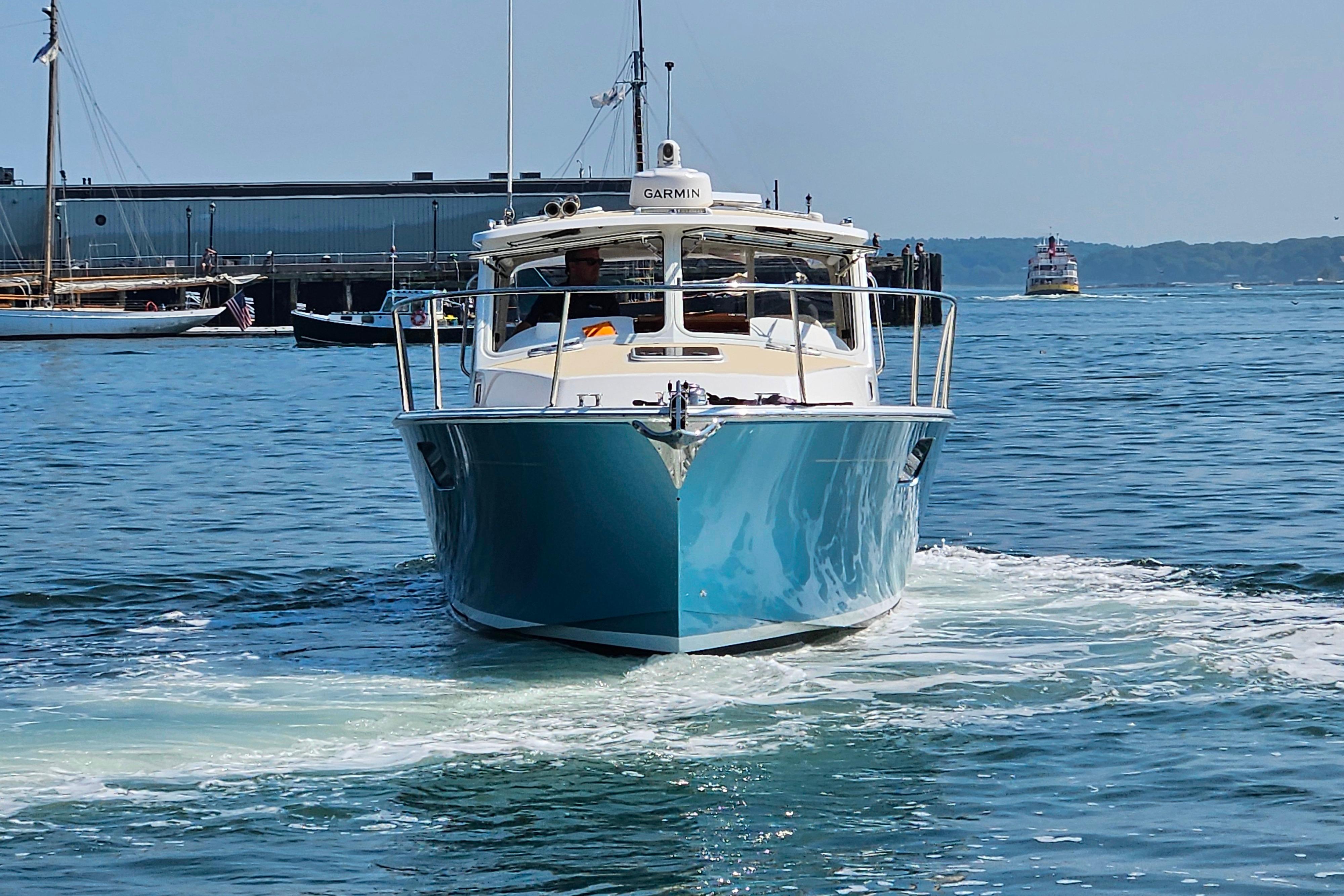 2023 MJM 35 boat cruising in a harbor with clear blue water.
