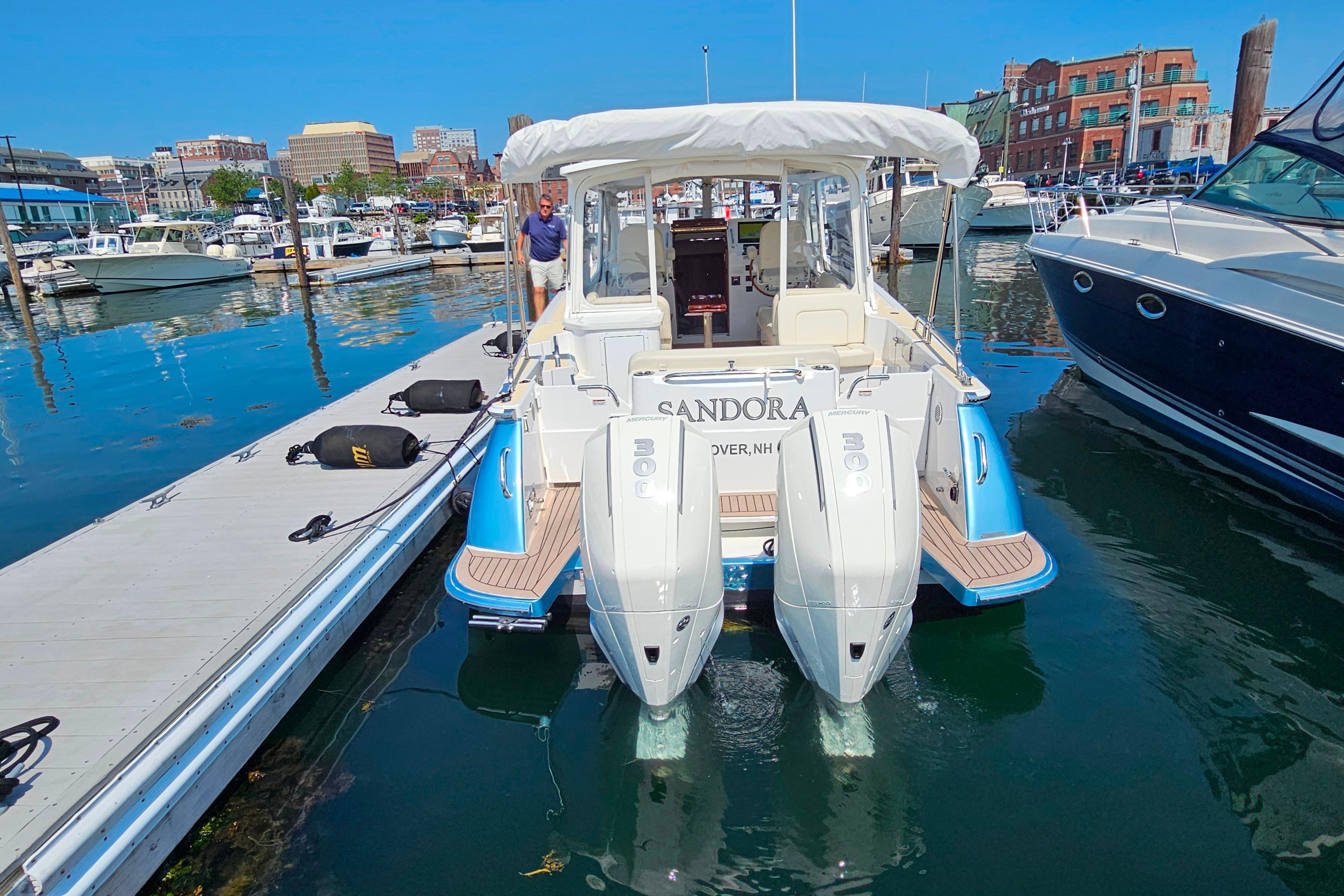2023 MJM 35 boat docked at marina with twin engines and cityscape background.