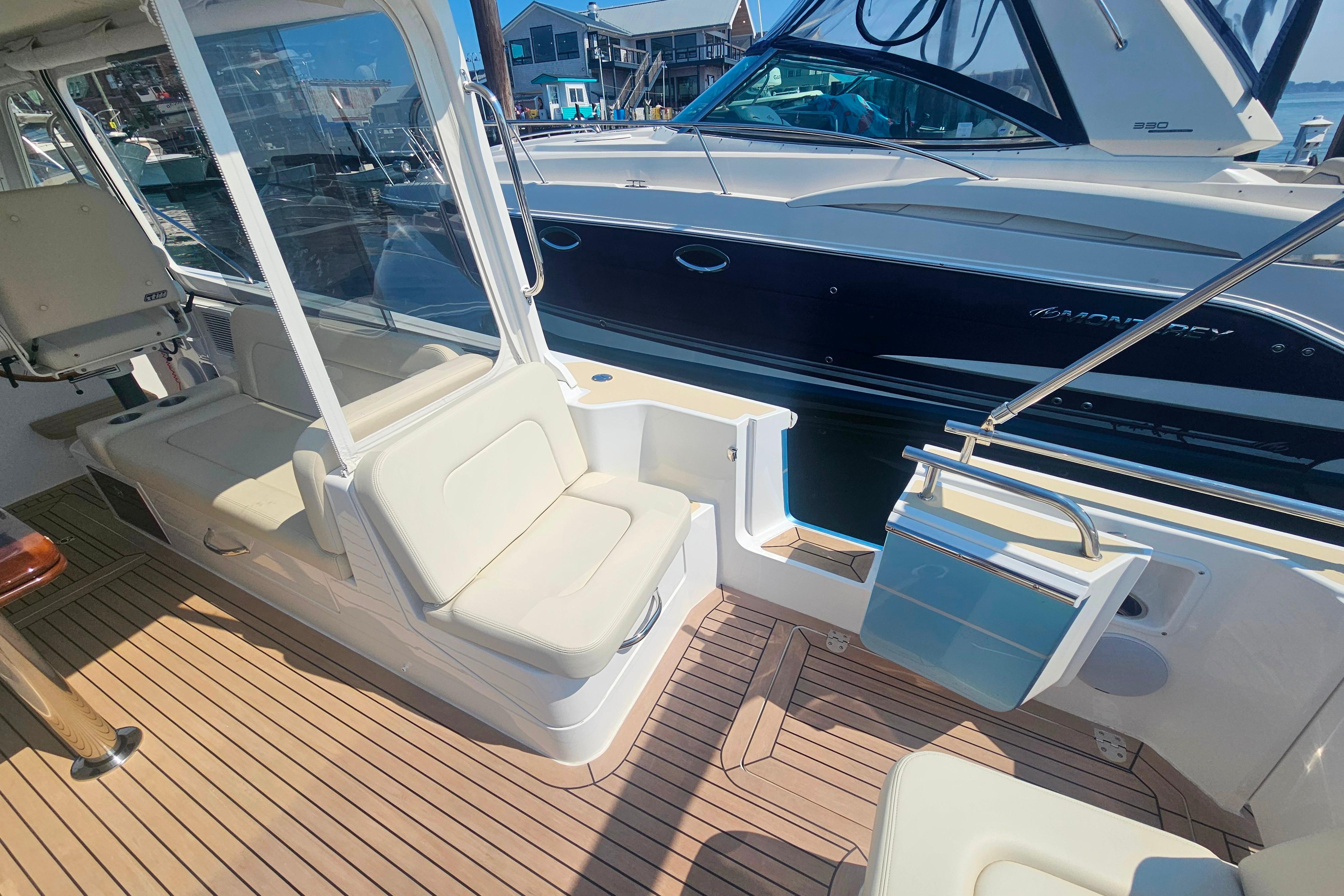 2023 MJM 35 boat interior with seating and wooden deck, docked beside another vessel.