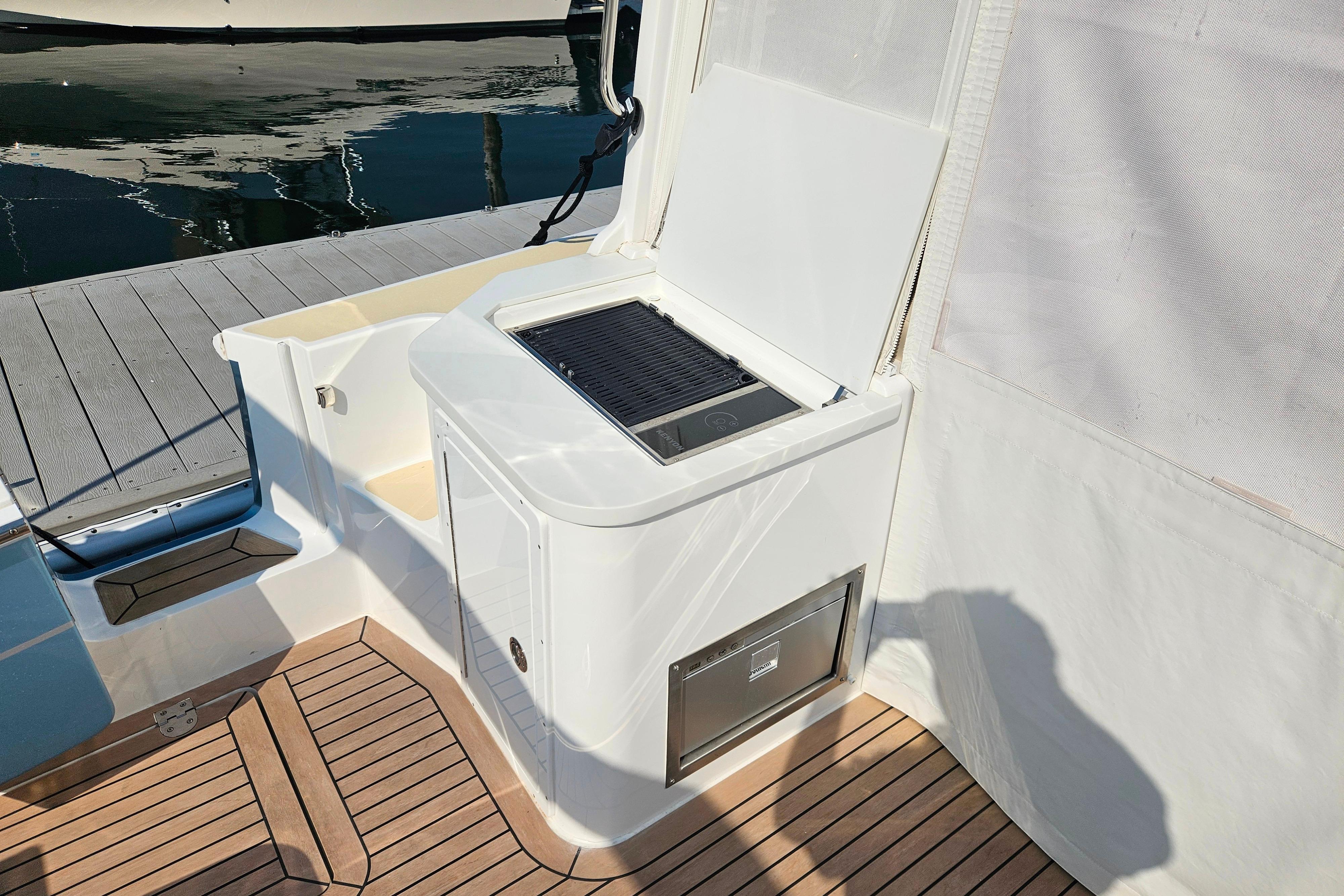 2023 MJM 35 yacht deck with built-in grill and storage, docked by the water.