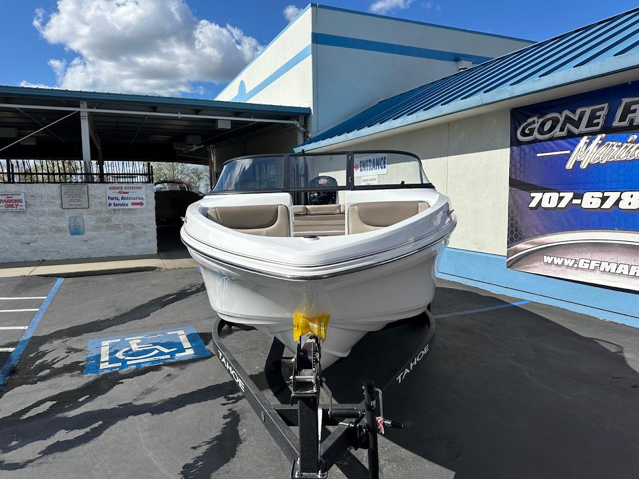 2025 Tahoe 185 S boat on trailer, parked outside dealership under blue sky.