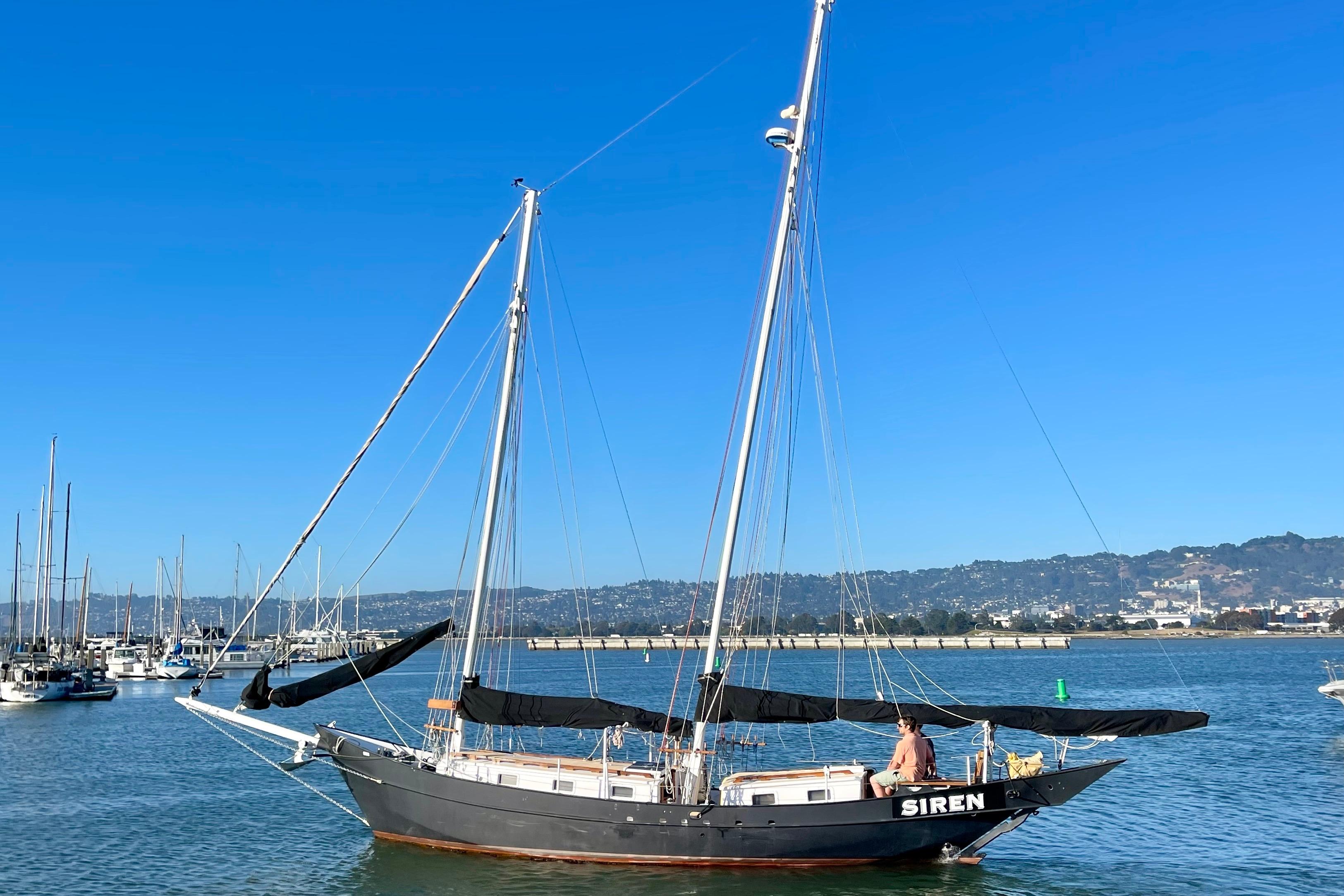 Sailboat "Siren" on calm waters, Pinky Custom 2008 model, under clear blue sky.